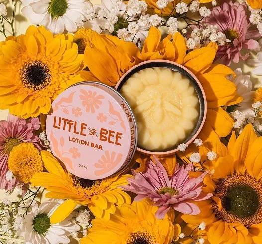 Flatlay of Little Bee lotion bar tin on top of bed of flowers