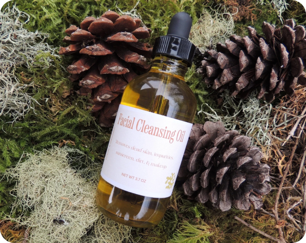 Oly Sudz facial cleansing oil product laying on a bed of moss and pinecones