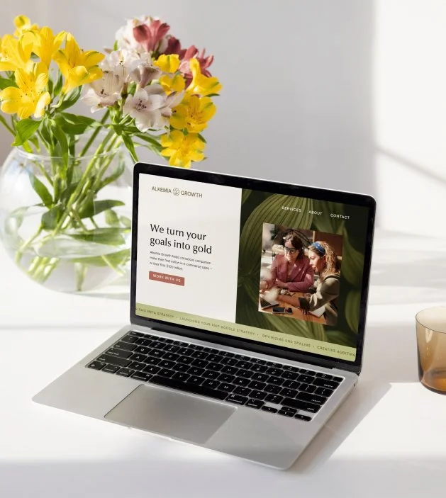 Website mockup on a laptop with vase of flowers in background