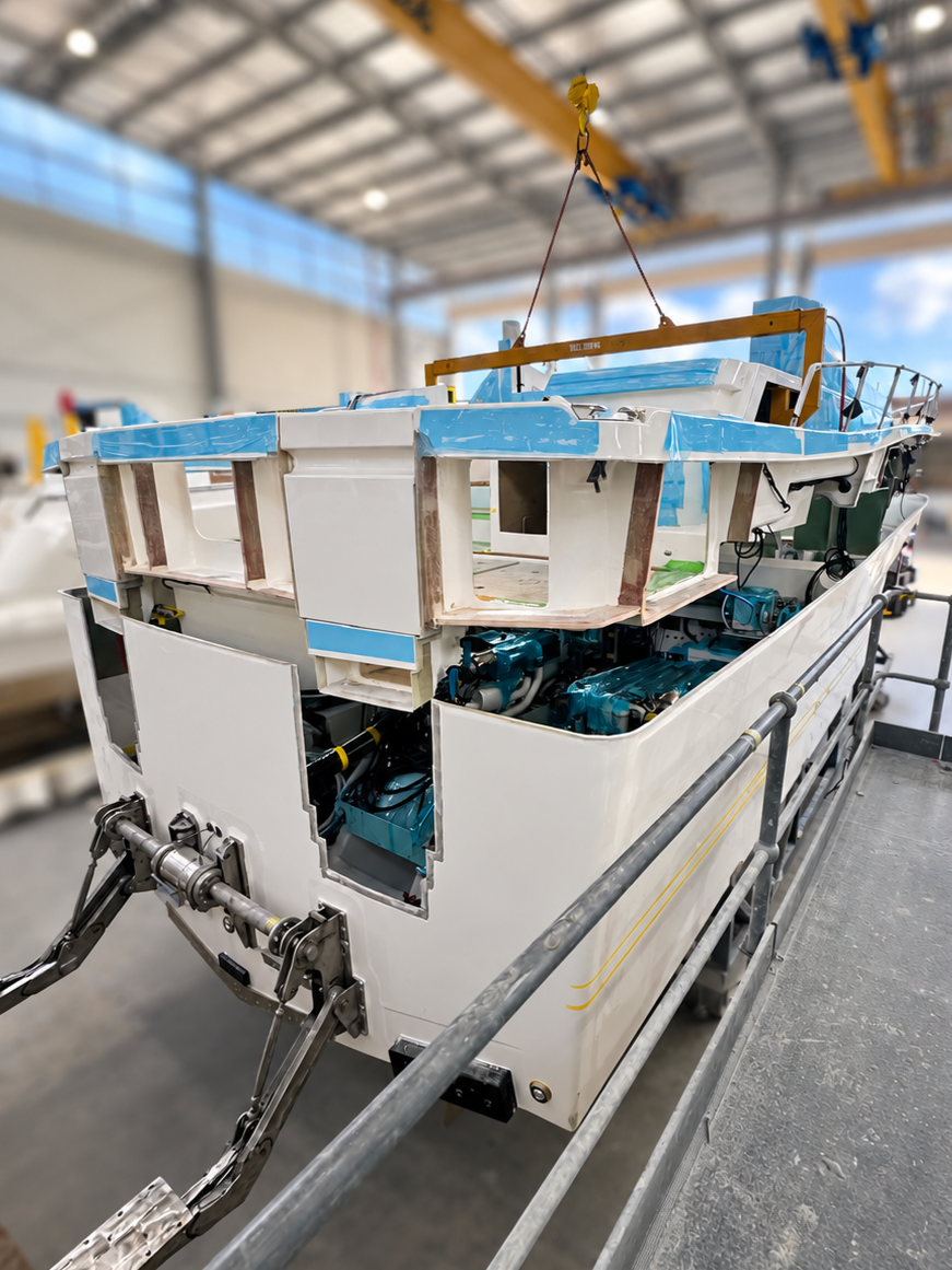 Motor yacht deck structure being lifted and lowered into position during hull and deck joining process using overhead gantry cranes in production boatbuilding on the Gold Coast