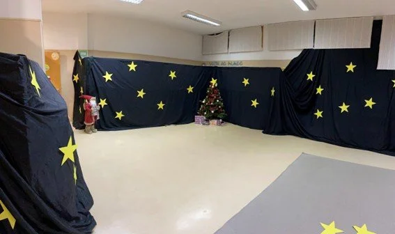 Decoração de Natal com fundo preto, estrelas amarelas e uma pequena árvore de Natal