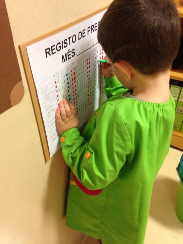 Criança anotando pontos em um quadro de controle de presença na escola.