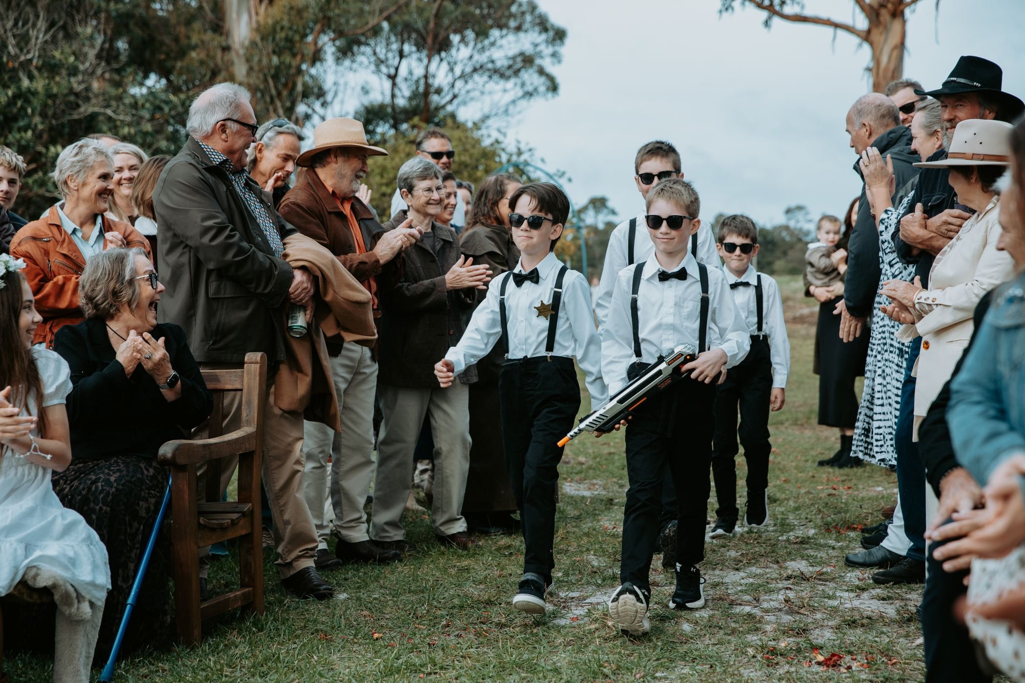 Group of people outdoors at a wedding ceremony in Albany WA.. Boys are walking the aisle before the bride and groom.