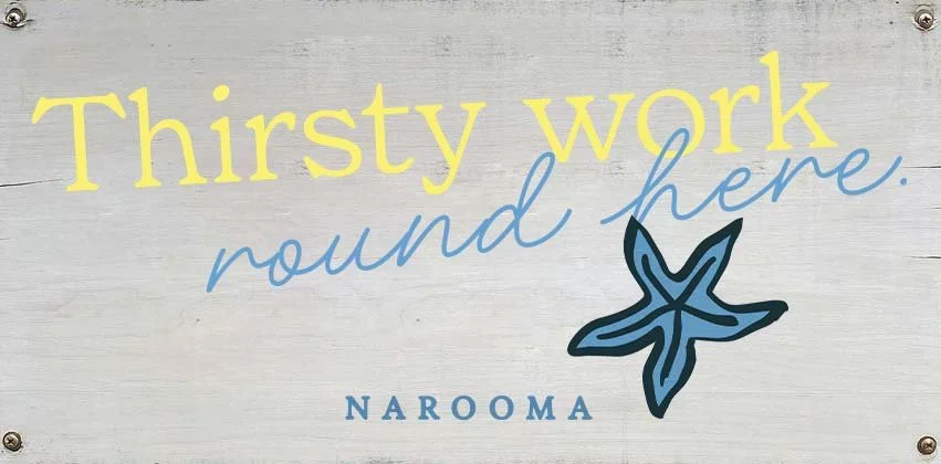 Sign with the words 'Thirsty work round here.' and an illustration of a starfish, with the text 'NAROOMA' below.