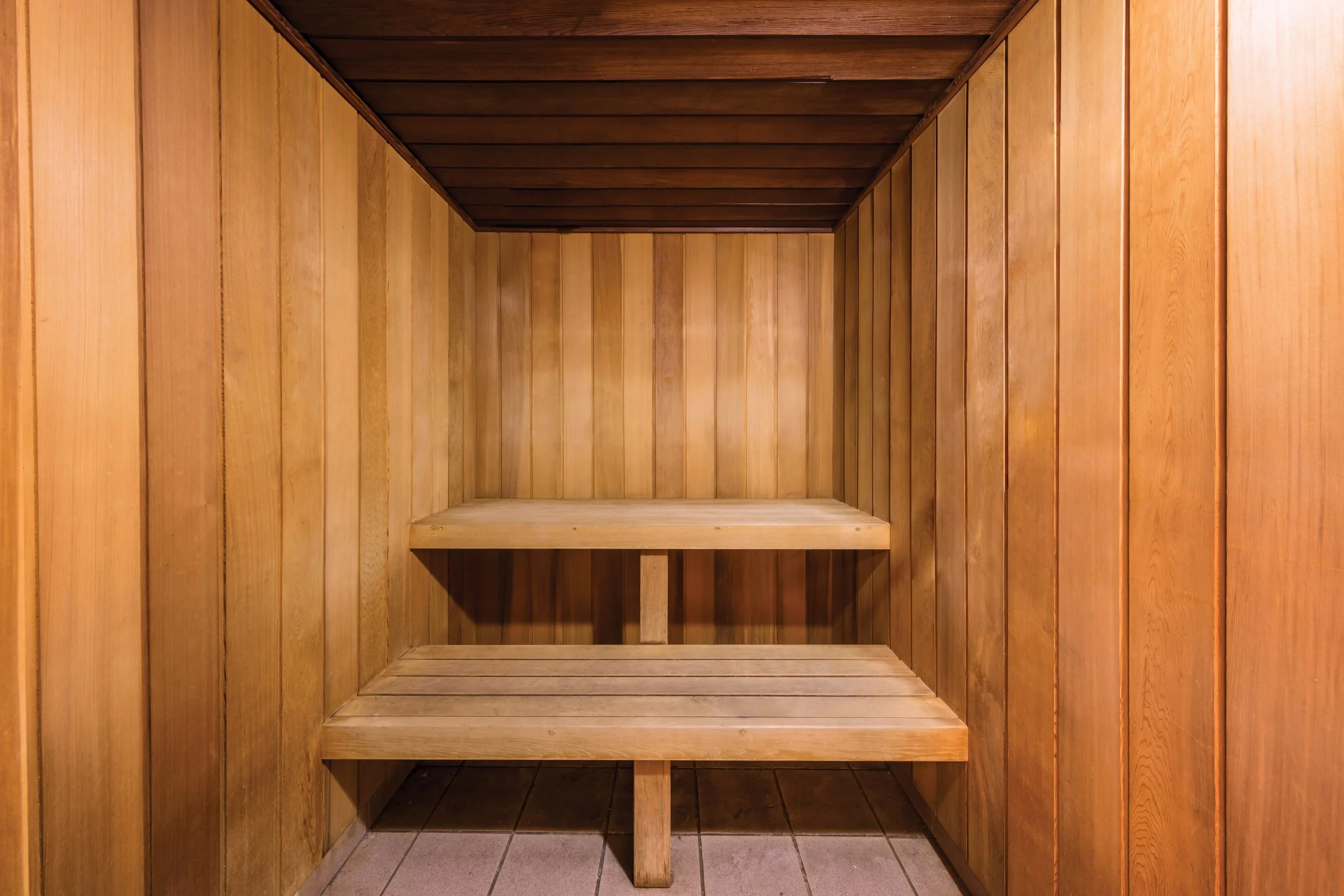 Empty wooden closet or cabinet with shelves, built-in walls, and a tiled floor.