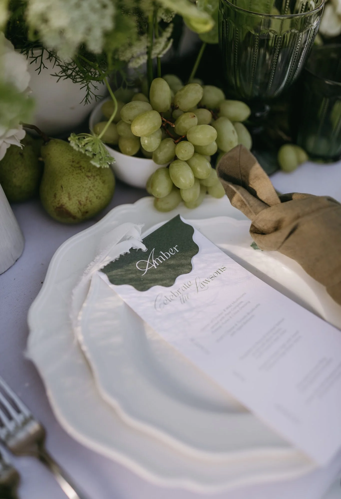 Grapes, pears, and a glass in a floral arrangement with a card labeled "Amber".
