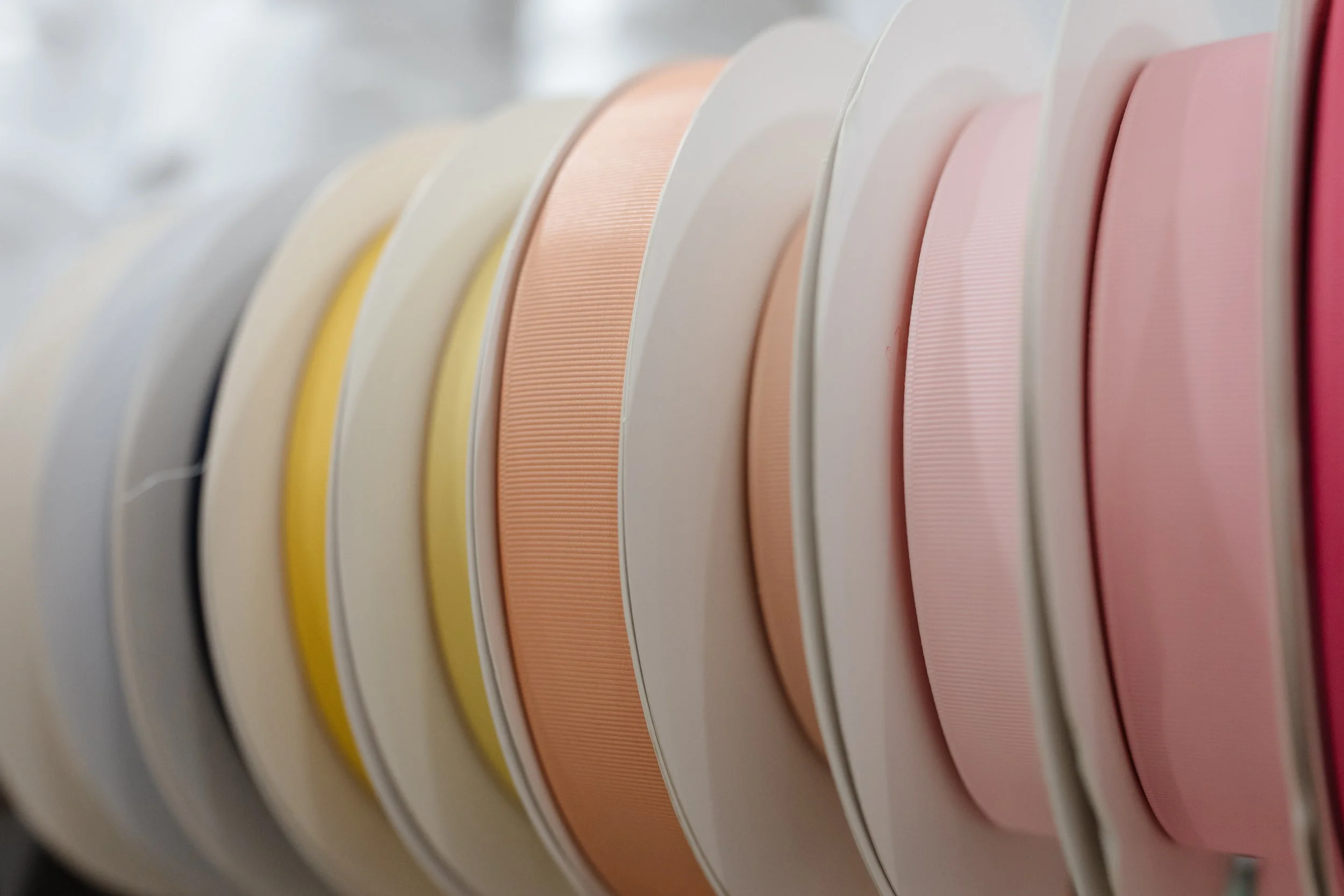 Close-up of pastel-colored yarn spools arranged in a row.