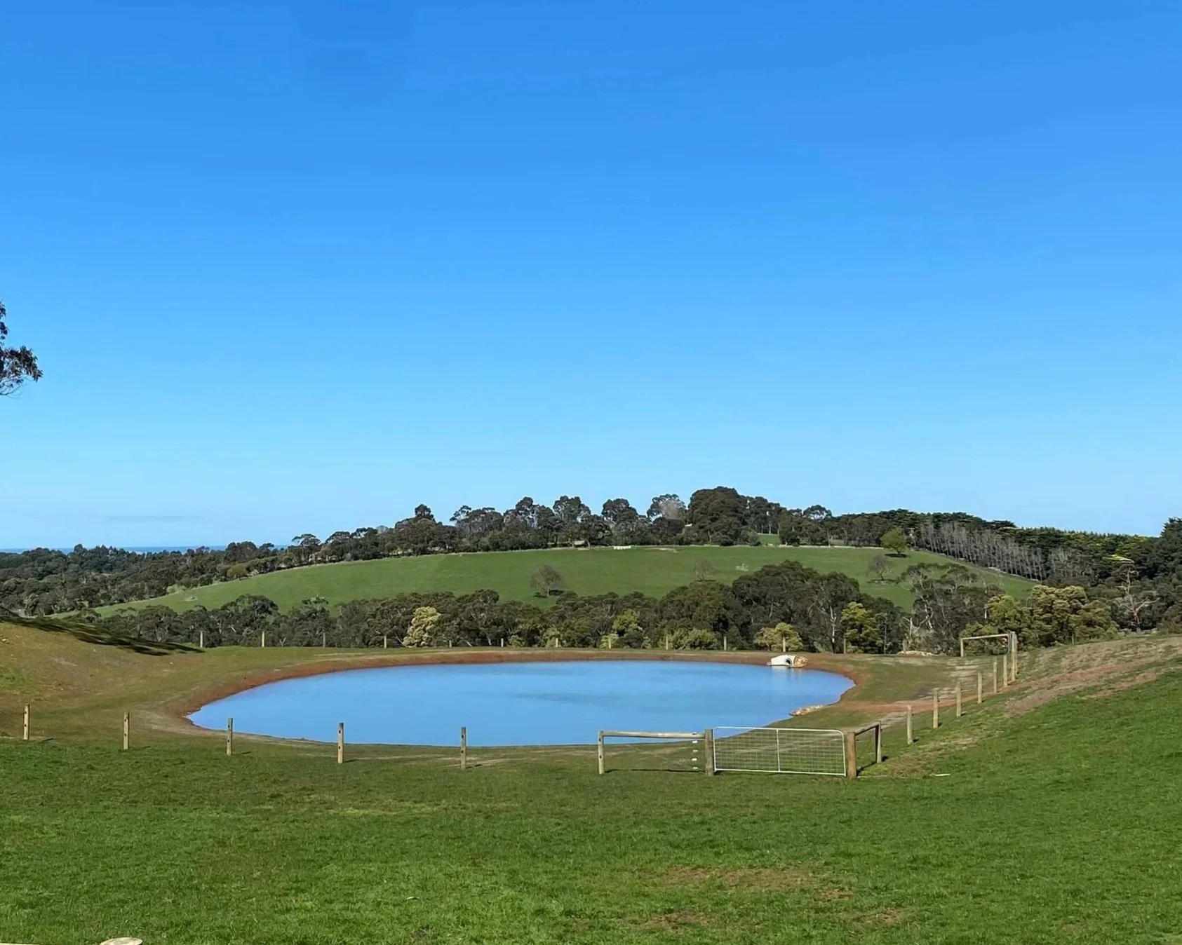 A pristine dam with no weeds, accessible surrounds and clear water that is reflecting the blue sky.