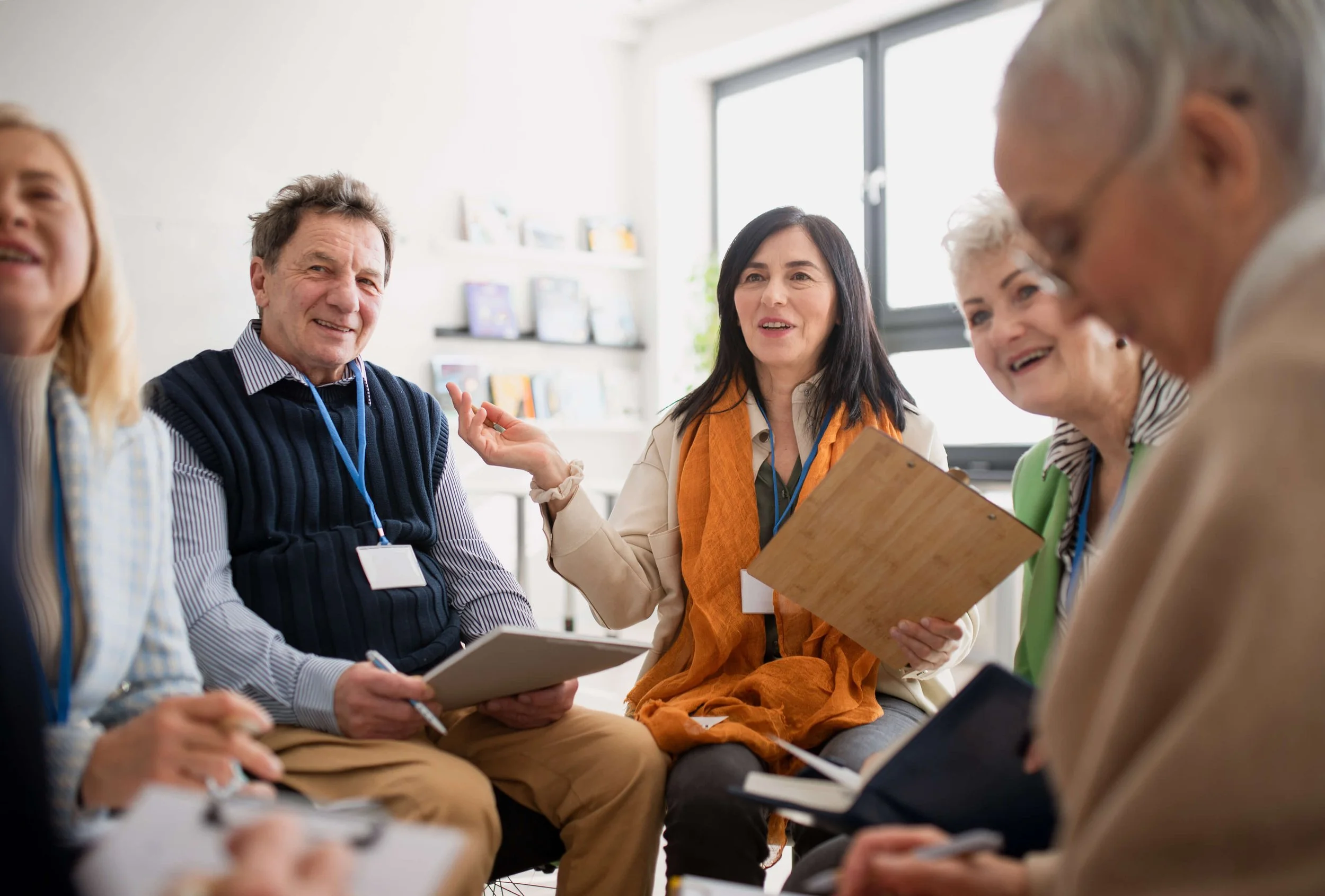 Group of diverse people sitting in a circle, engaging in a discussion or meeting while indoors.
