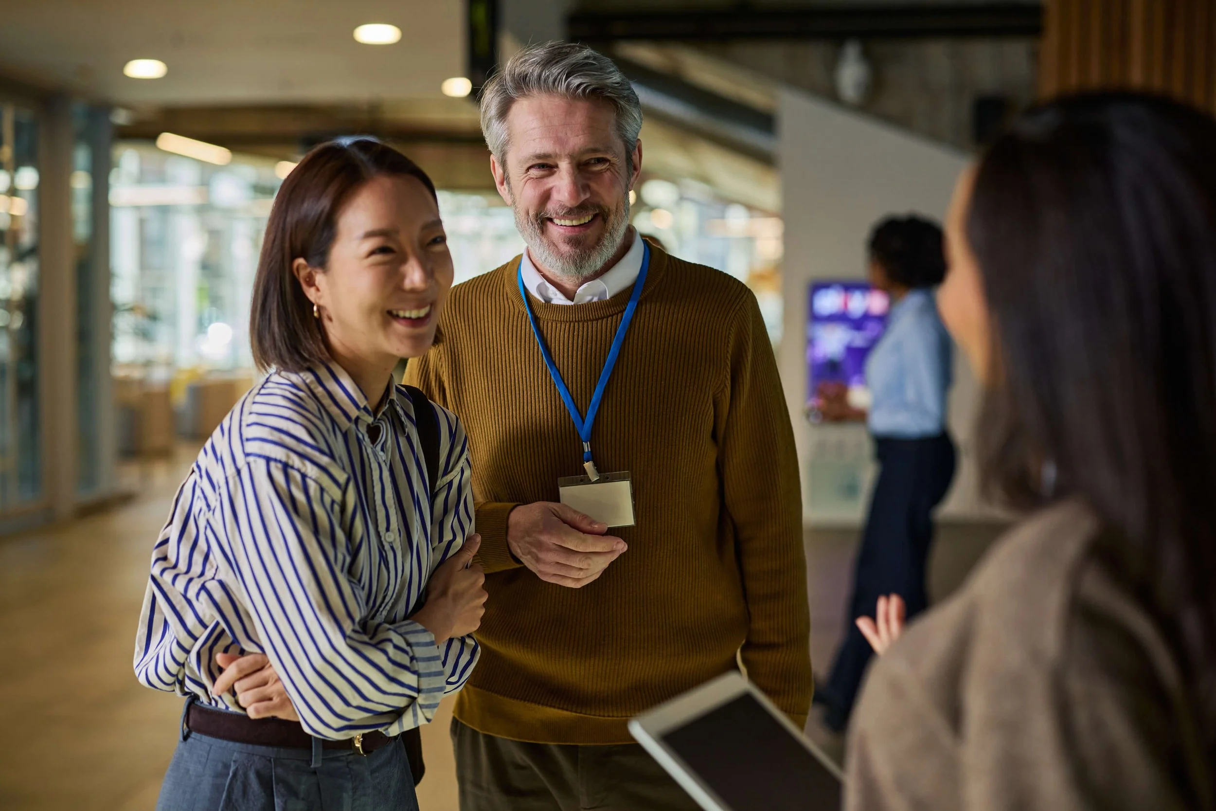People talking in a modern indoor space, smiling and interacting.