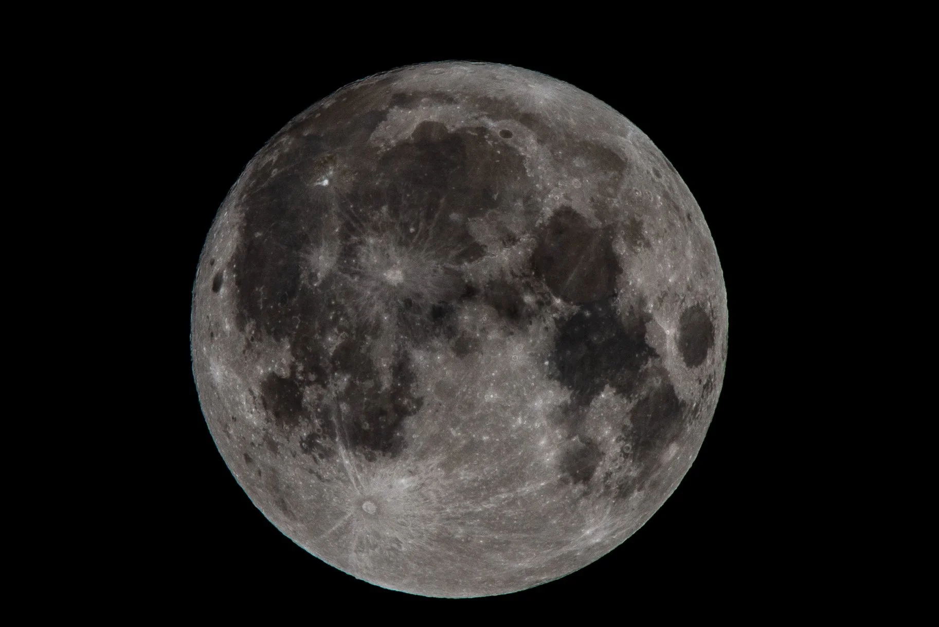 Close-up of the full moon showing its craters and surface details against a black night sky.
