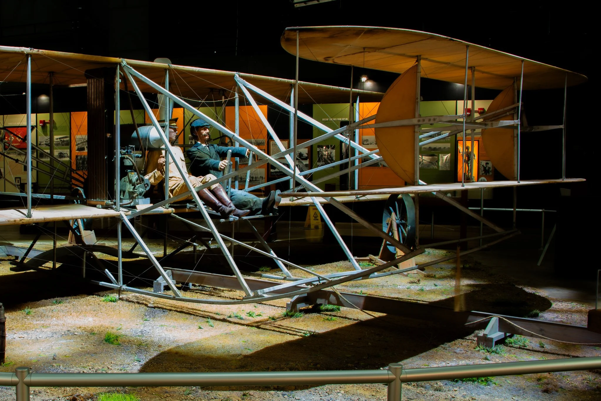 Museum exhibit featuring two mannequins dressed as early aviators in an early airplane frame.