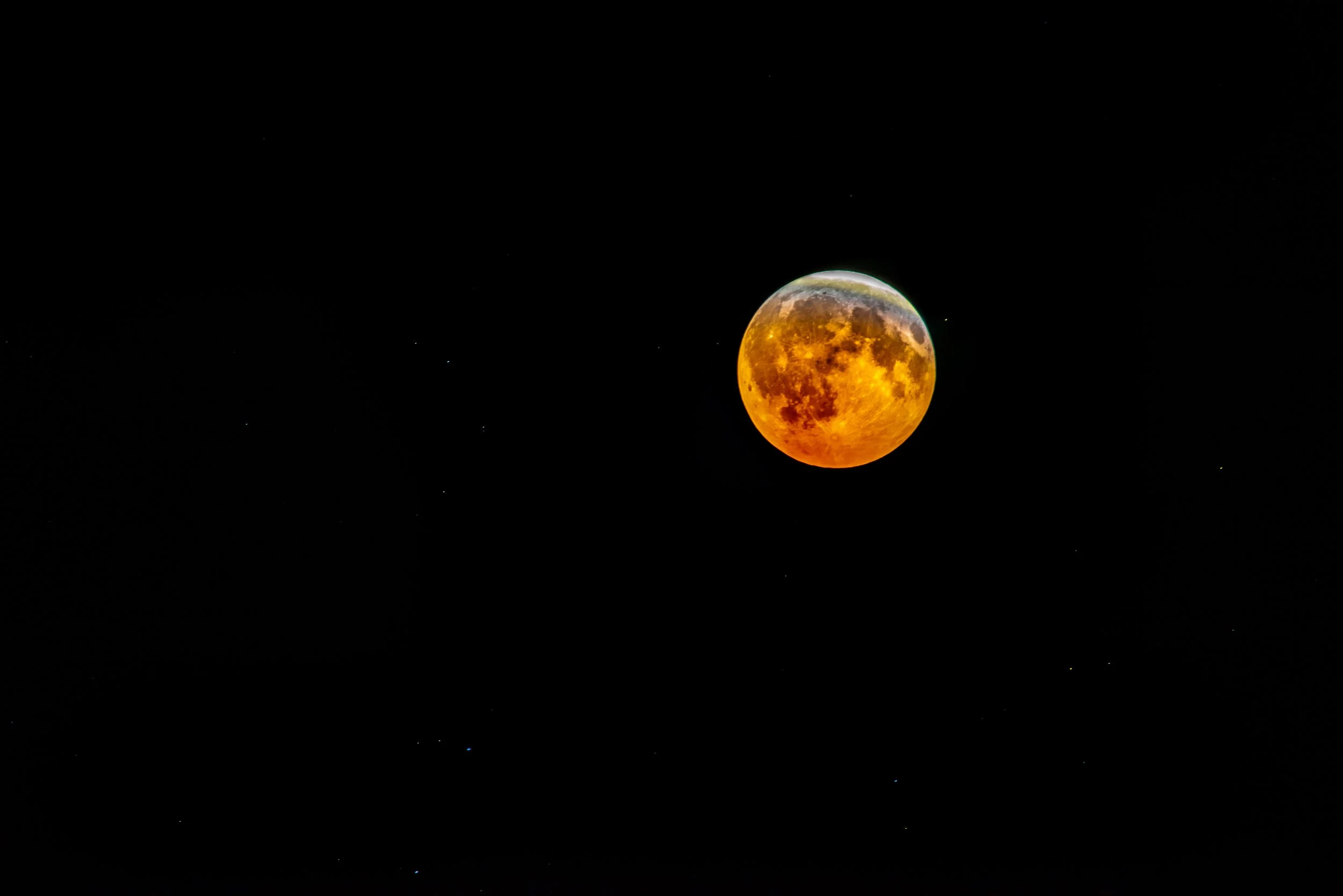 A large orange moon against a dark night sky with scattered stars.