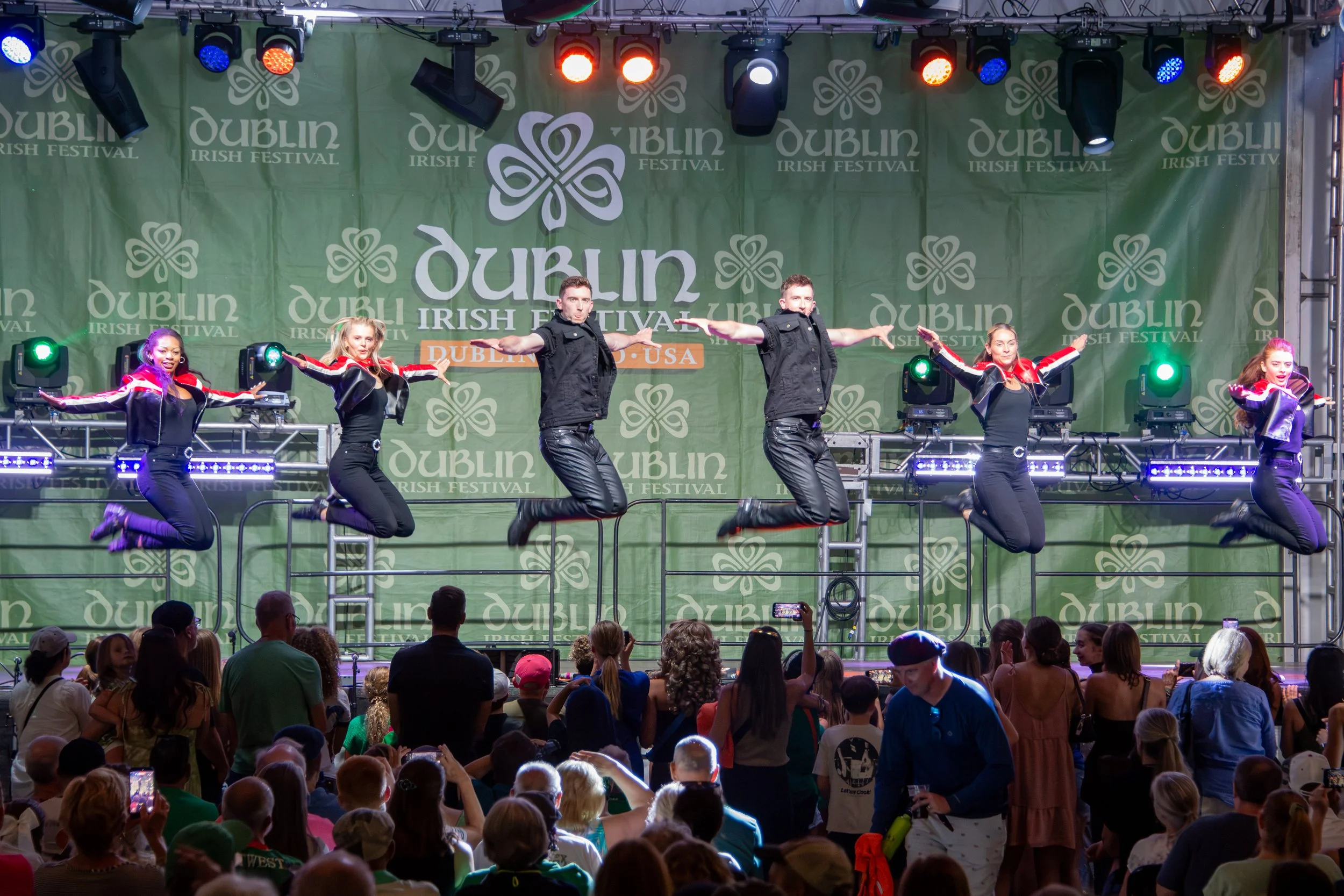 The Gardiner Brothers full troop performing on a stage at the Dublin Irish Festival, with colorful stage lights and an audience watching.  Photographed by Cattywampus Camera.