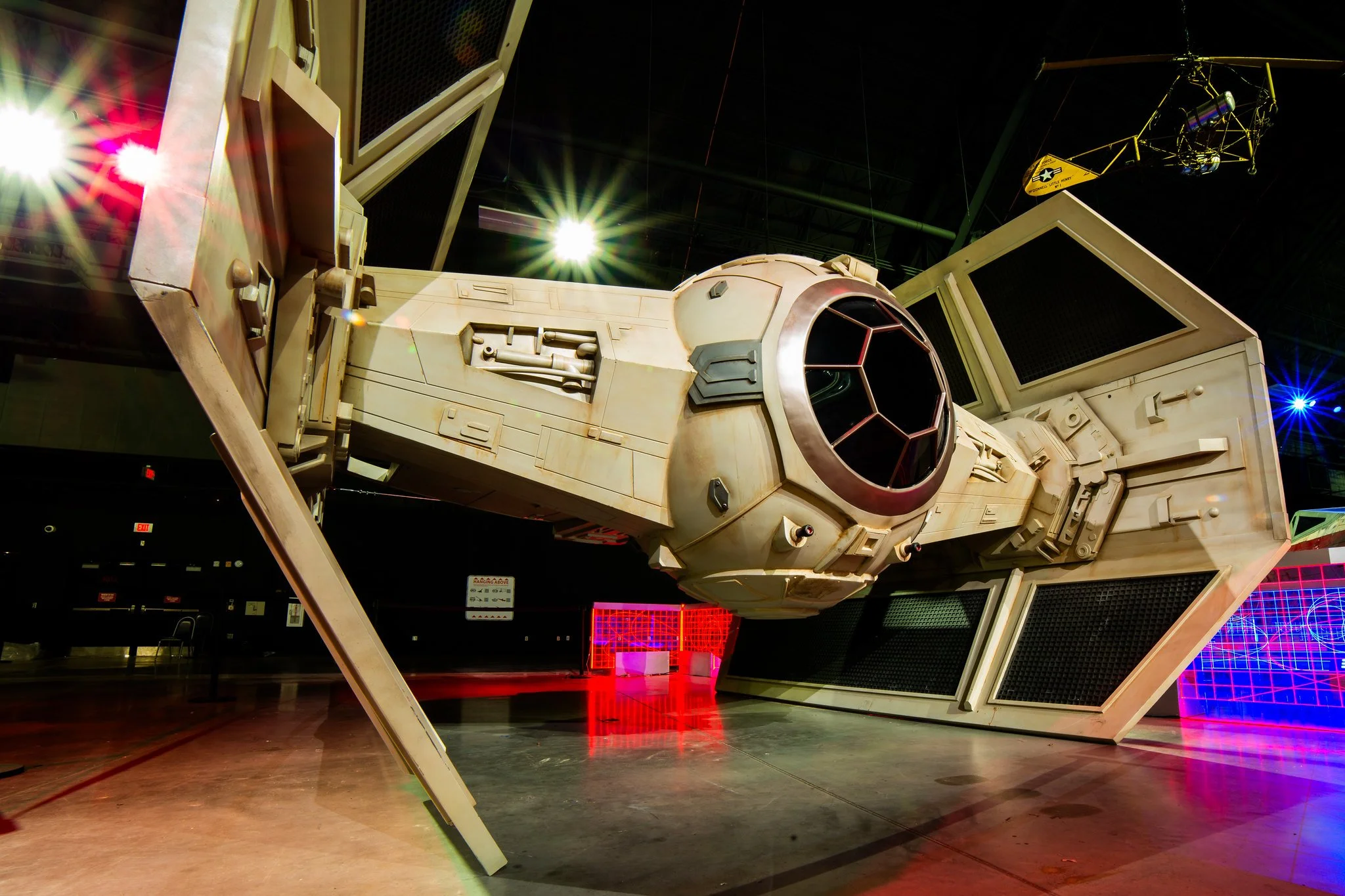 Model of the Millennium Falcon from Star Wars displayed indoors with laser lights and display screens around it.