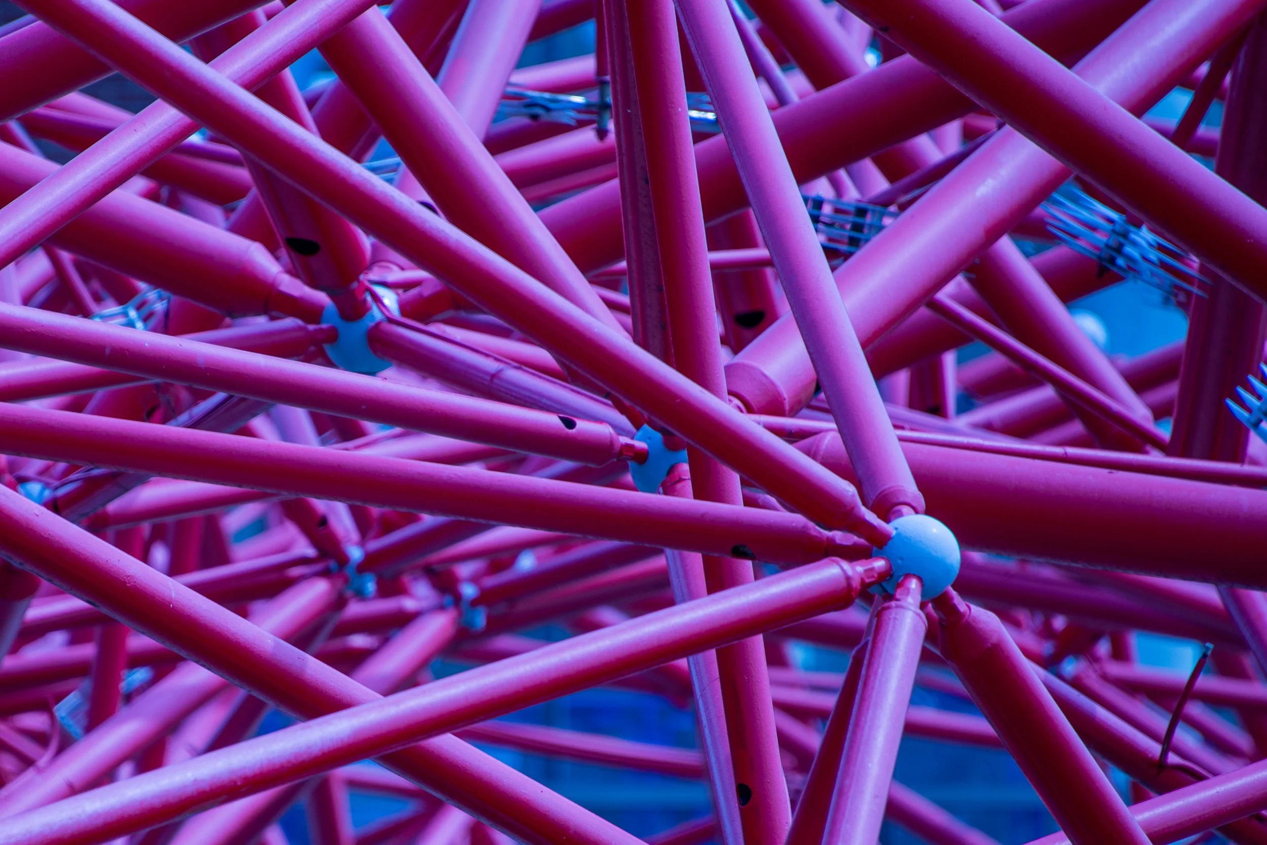 Close-up view of pink intertwined bicycle frames with blue connectors.