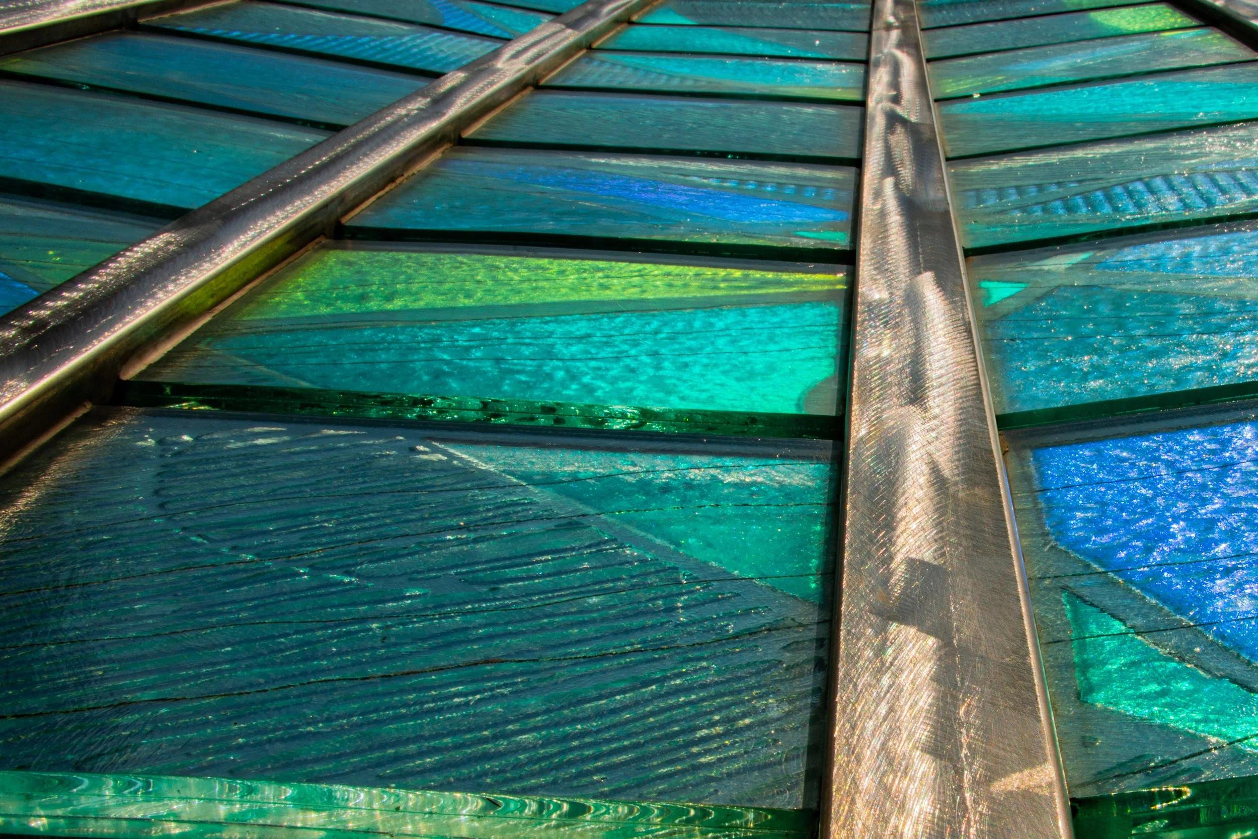Close-up of a colorful stained glass window with metallic framing.
