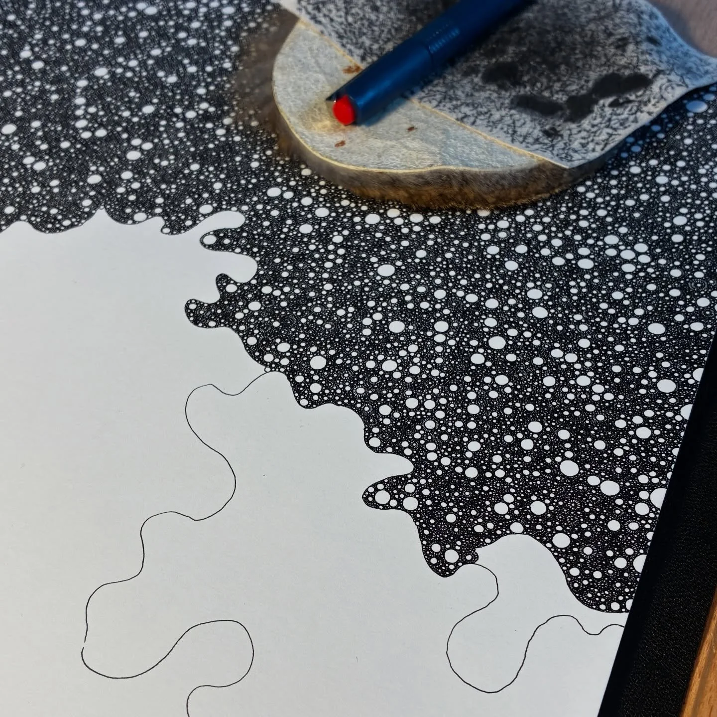 Detail shot of ongoing process art by Abdushakur, displaying the transition from clean organic boundary lines into dense, cellular ink stippling on paper.