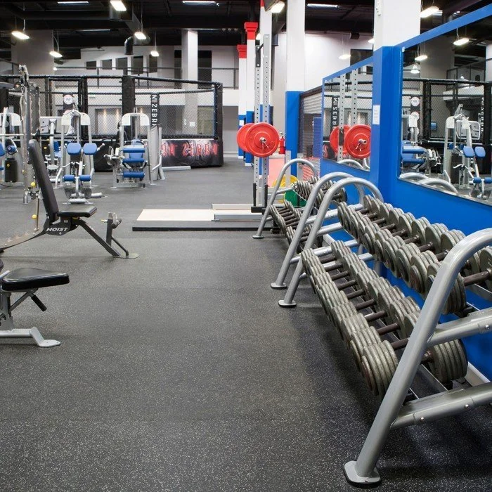 Empty gym with weight racks, exercise machines, and a mirrored wall.