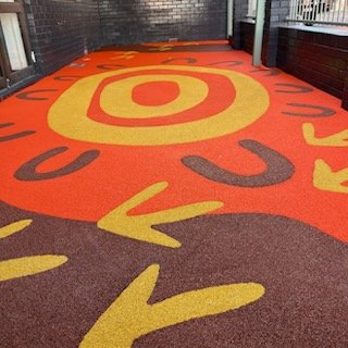 Colorful carpet with yellow, red, and black geometric patterns on a floor.