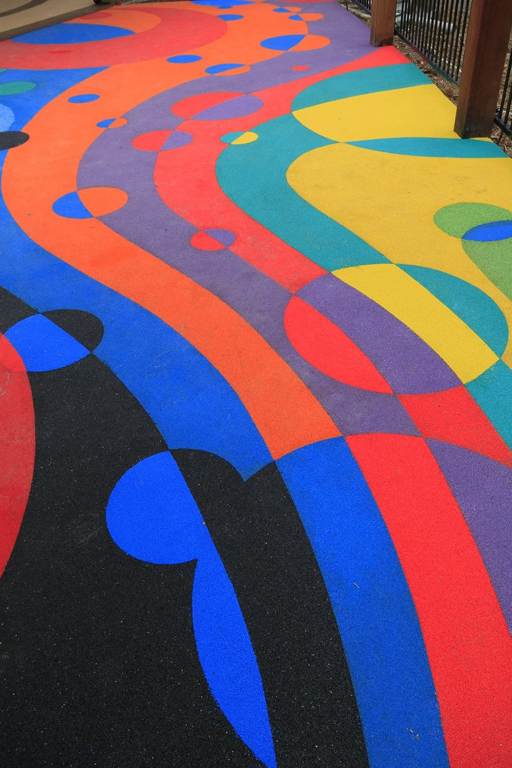 Colorful painted pathway with swirled and circular patterns, featuring bright colors like blue, orange, purple, yellow, green, and black.