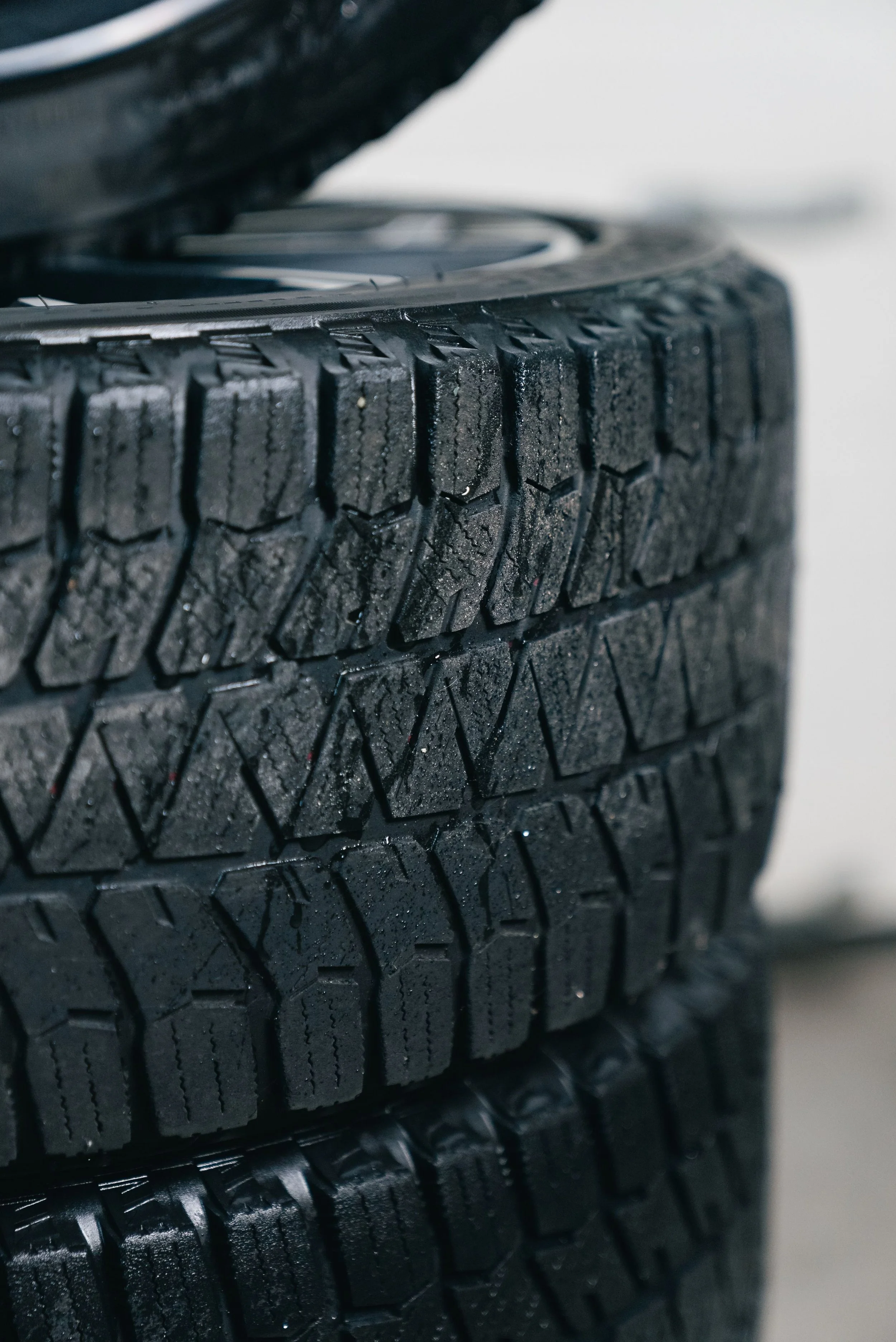 Close-up view of stacked black rubber tires with detailed tread patterns.