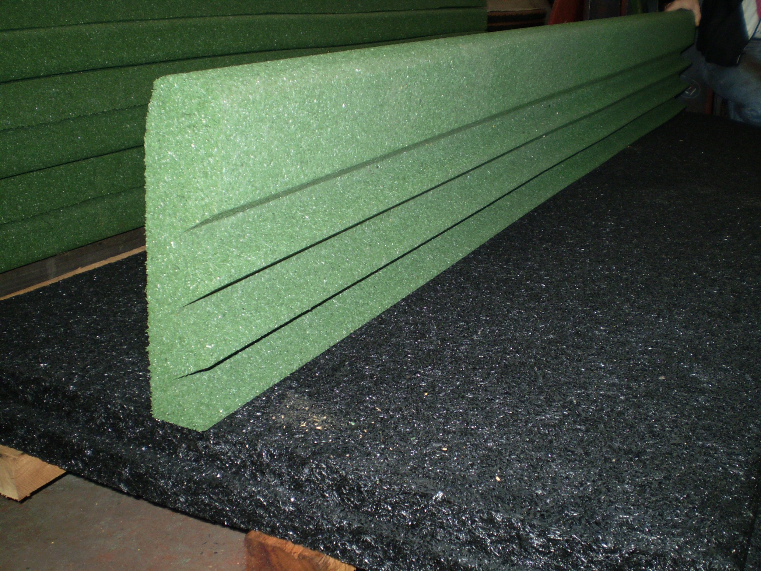 Green foam boards stacked on a black speckled countertop with a person holding one of the boards on the right side.