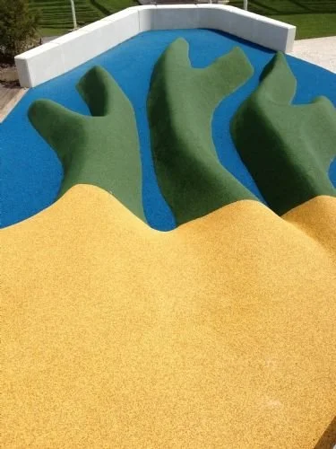 Colorful playground with a blue pool, green shapes resembling hands, and a yellow slide.