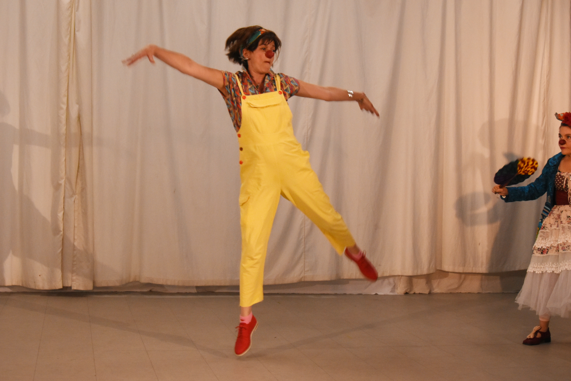 Une artiste en costume joue une scène de clown aérienne et pleine de mouvement.