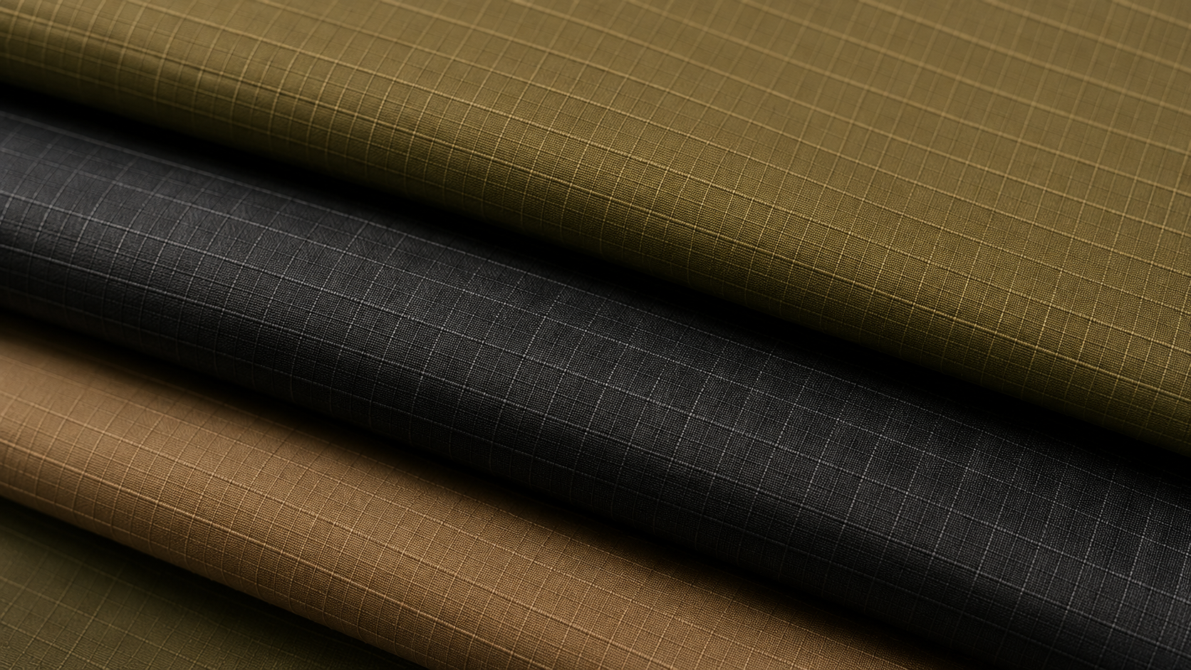 Stacked rolls of fabric with grid-like patterns in shades of green, black, and beige.