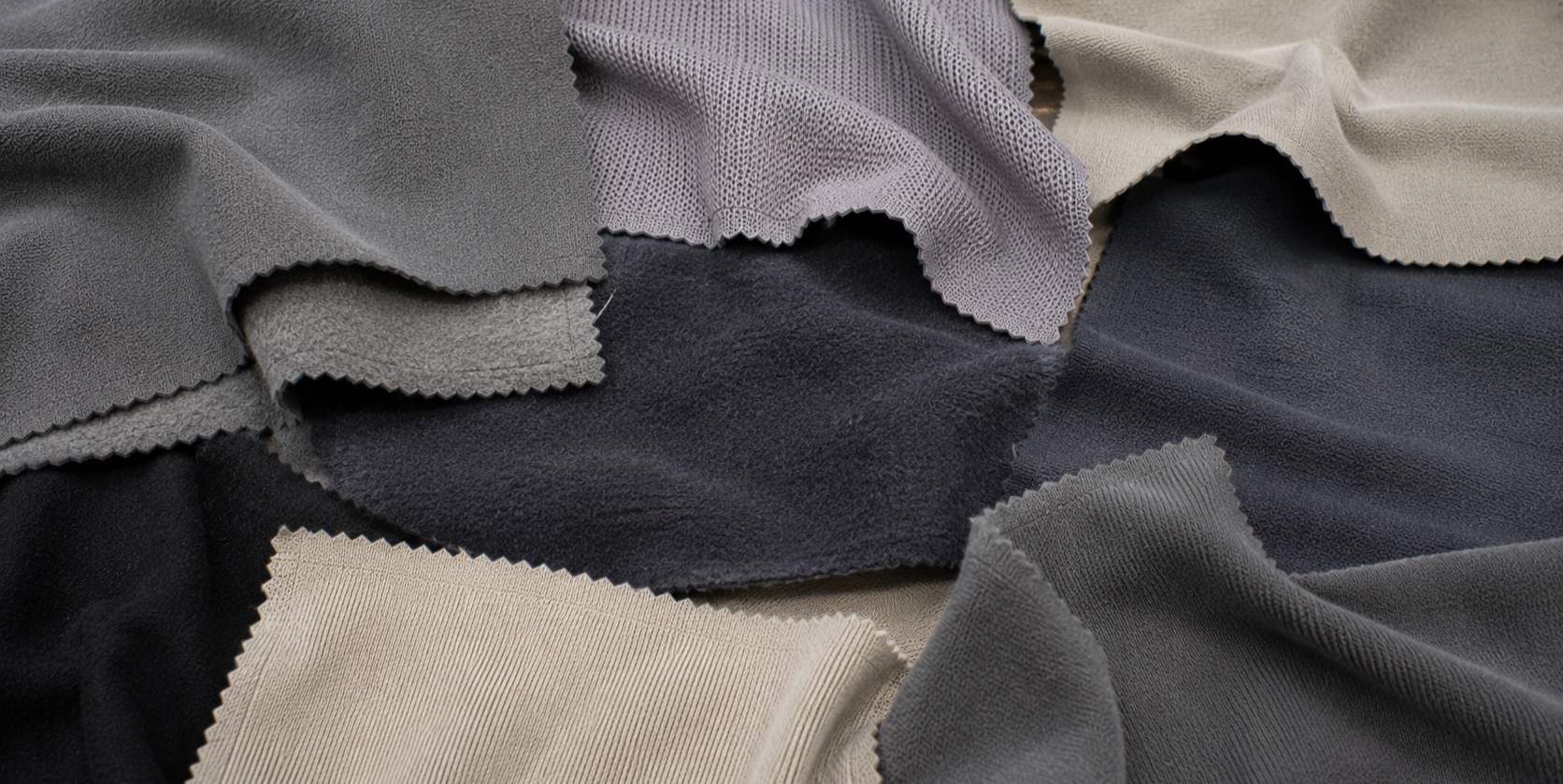 Various fabric swatches in shades of gray, black, and beige with different textures, arranged in overlapping layers.