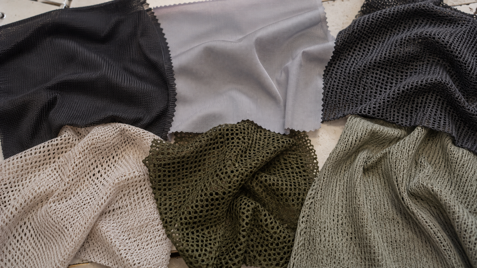 Assorted mesh and fabric swatches in black, gray, beige, and olive green colors.