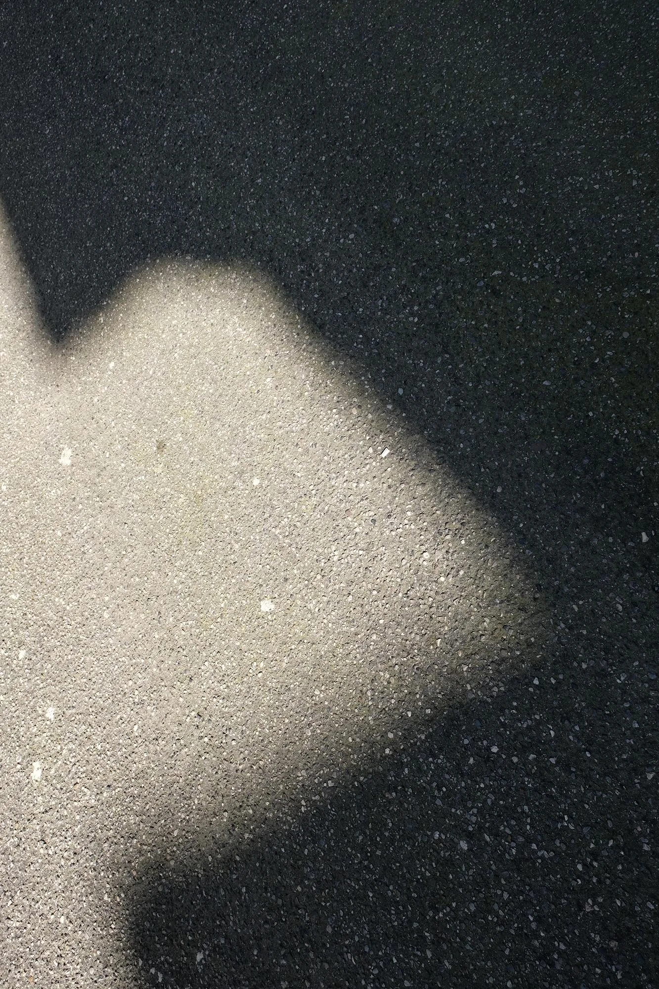 Aree di asfalto chiaro e nero, con una netta linea di transizione tra le due superfici lungo la metà superiore dell'immagine.