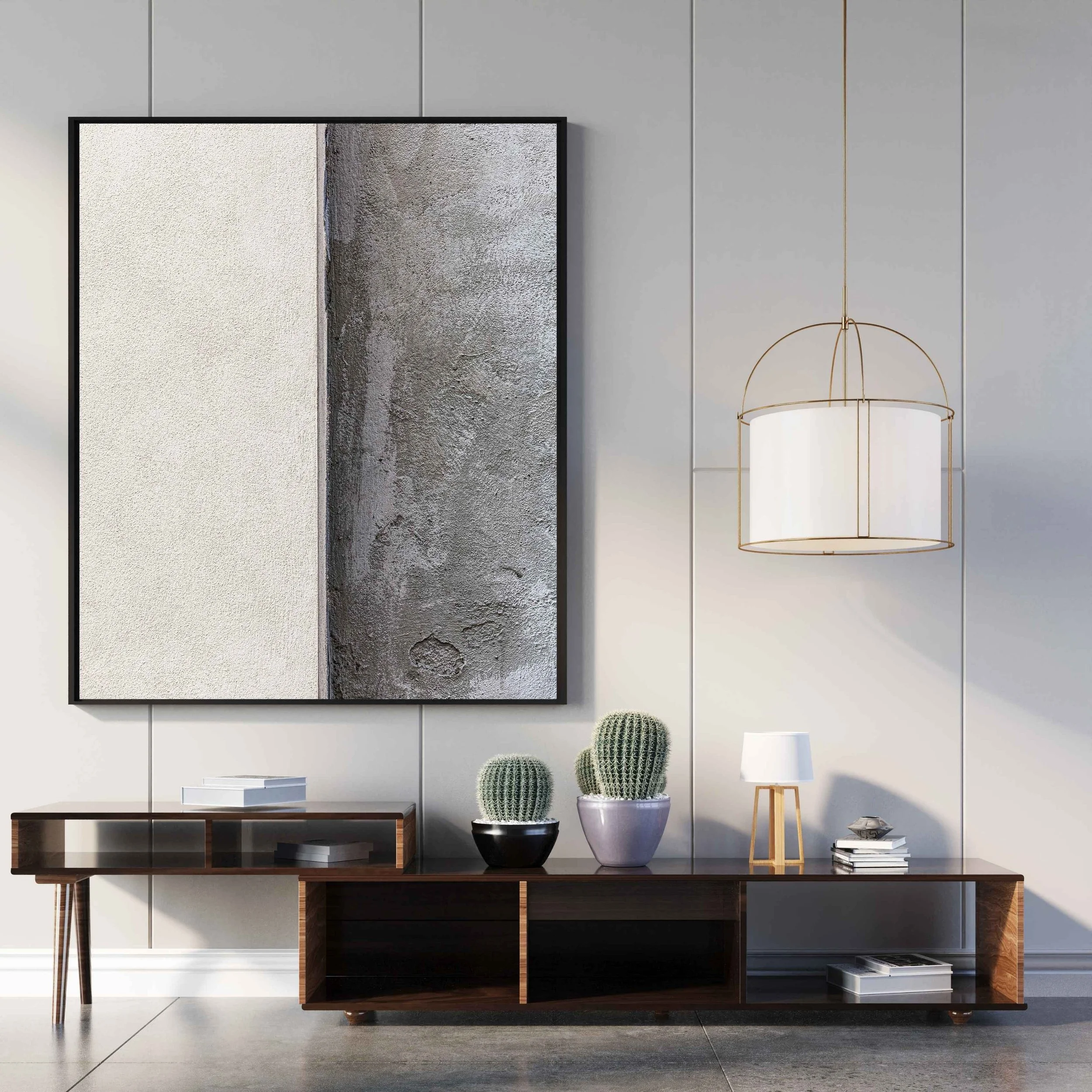 Interno moderno con mobile basso in legno scuro, piante di cactus in vasi, lampada a soffitto gialla, quadro astratto sulla parete con due blocchi colore nei toni del grigio, oggetti decorativi su una superficie bianca, pavimento in cemento.