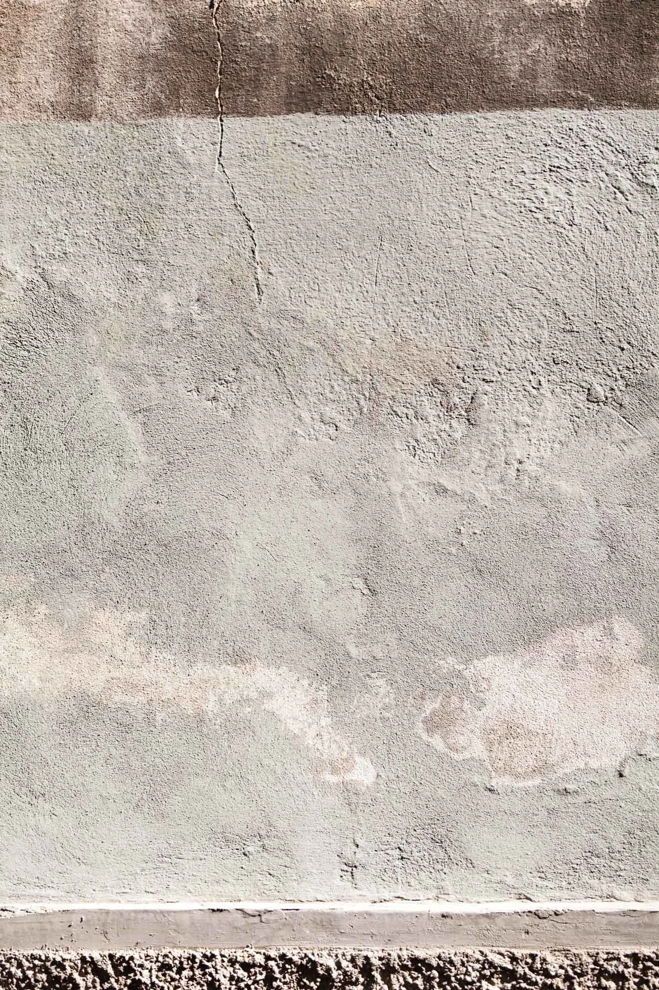 Foto di una parete in cemento con crepe verticali e variazioni di colore.