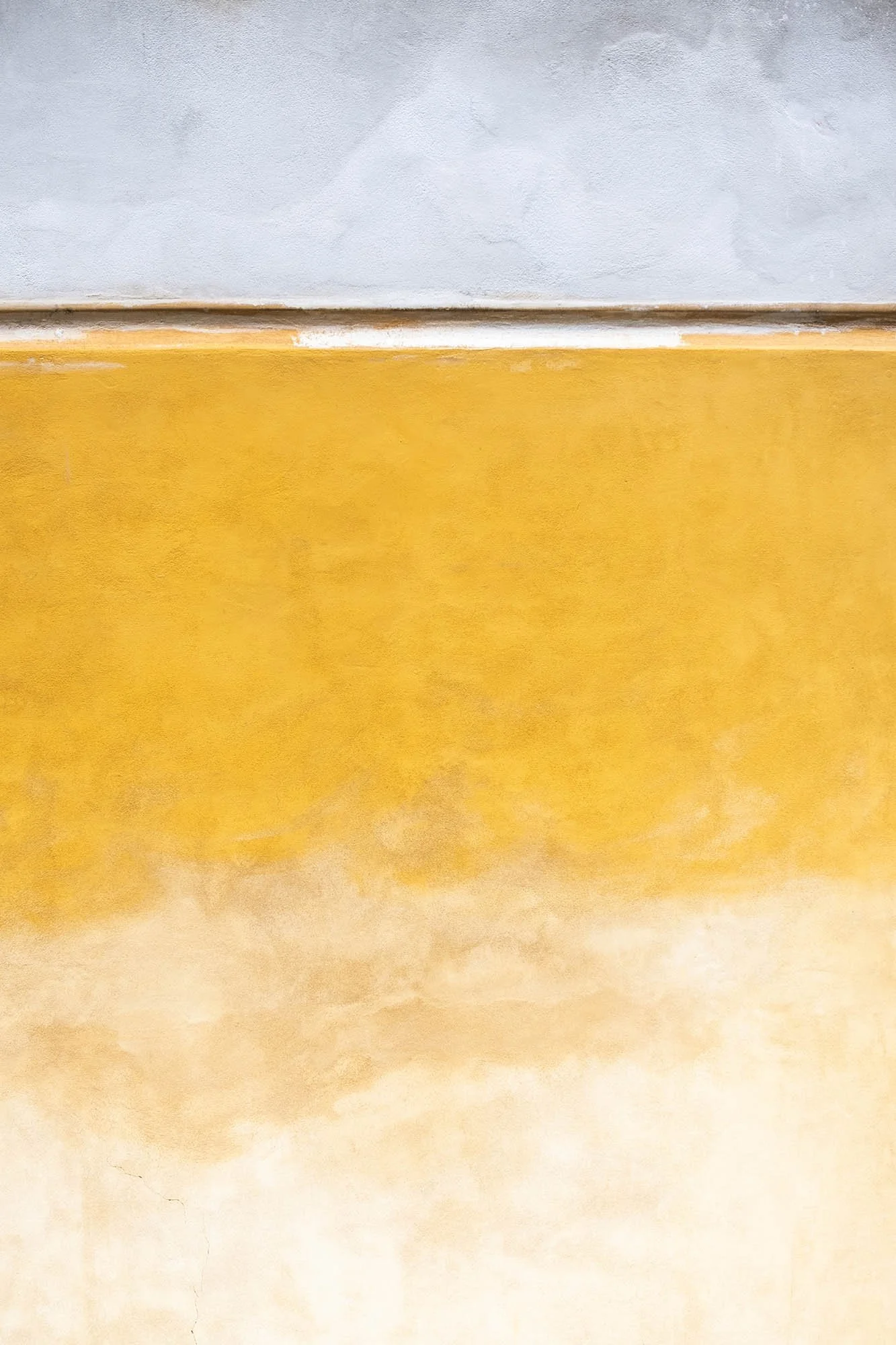 Dettaglio di una parete di muro con tinteggiatura a gradient color giallo e beige.