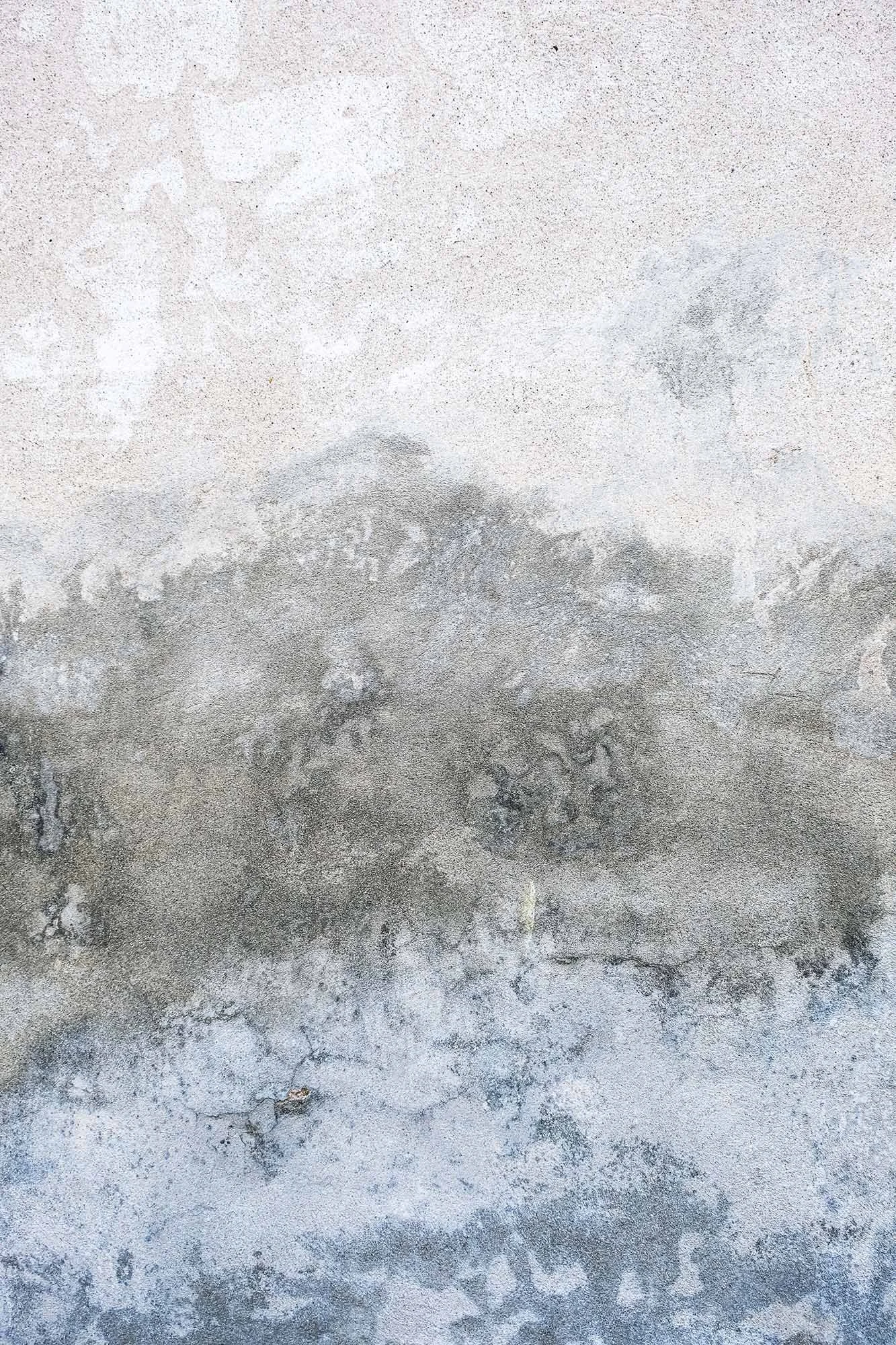 immagine astratta di un muro con diverse texture e colori grigi, che vanno dal chiaro allo scuro, evidenziando variazioni di superficie e imperfezioni.
