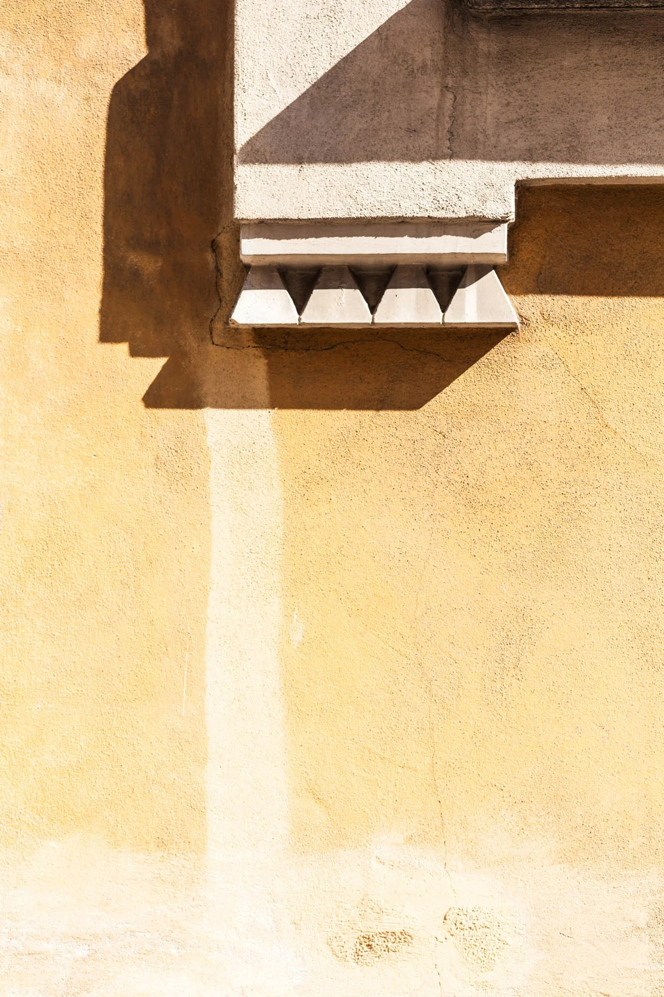 Un muro colorato con una sporgenza decorativa in cemento e un'ombra proiettata sulla parete