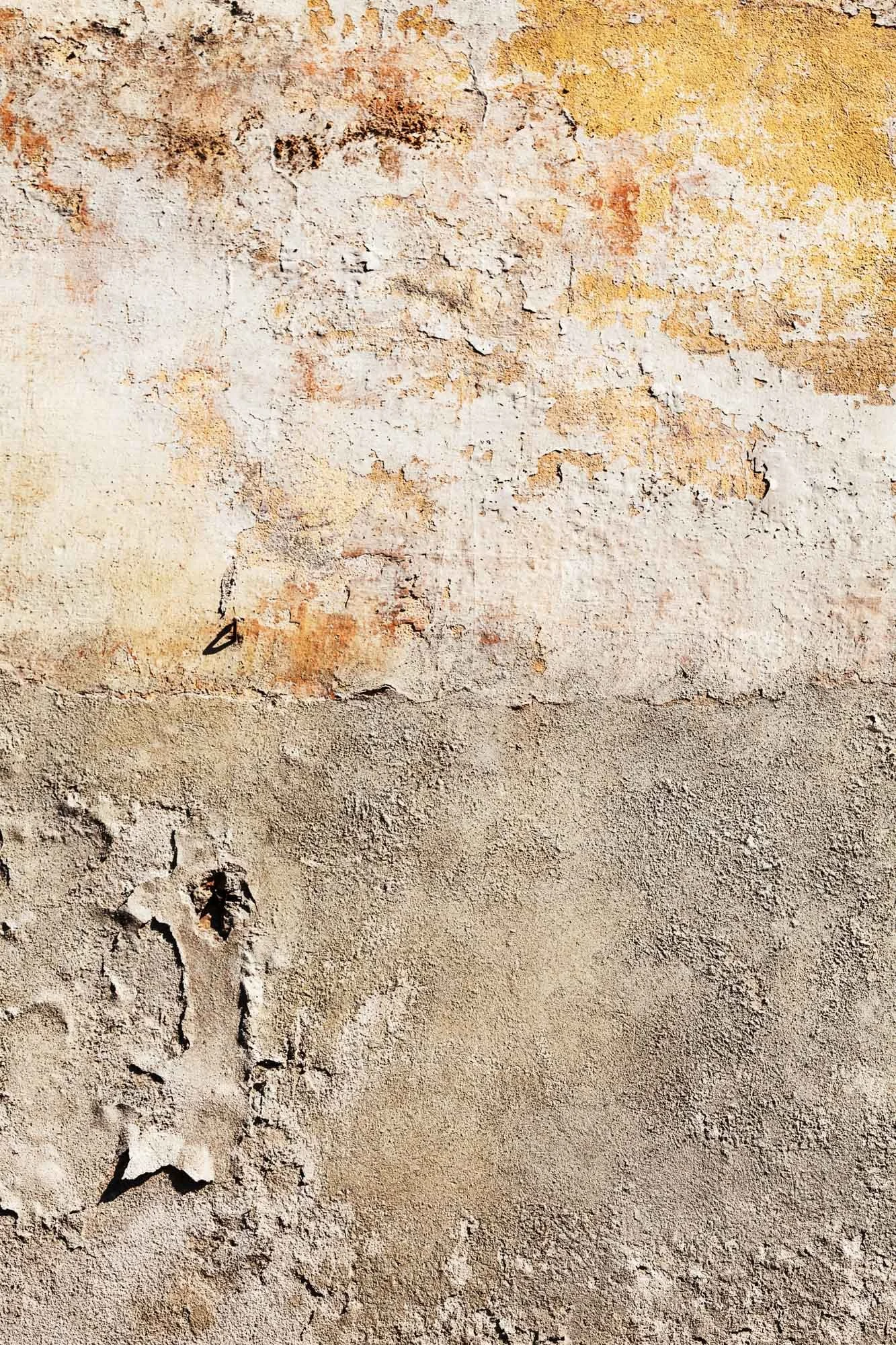 Superficie di un muro con vernice spaccata e degradata, mostrando crepe e desquamazione.
