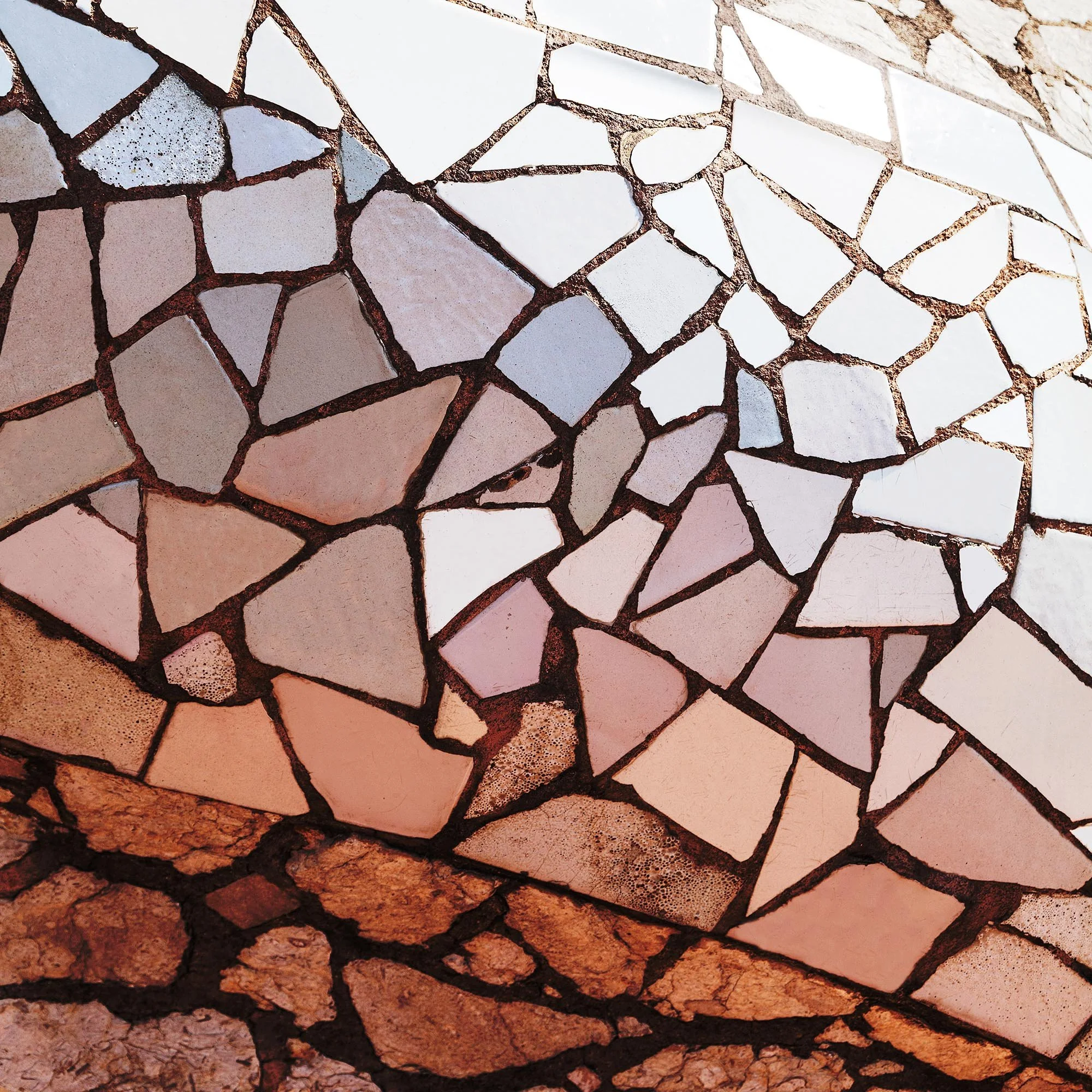 Una parete di pietra composta da pezzi di pietra di diverse forme e dimensioni, uniti tra loro con delle fughe di colore scuro.