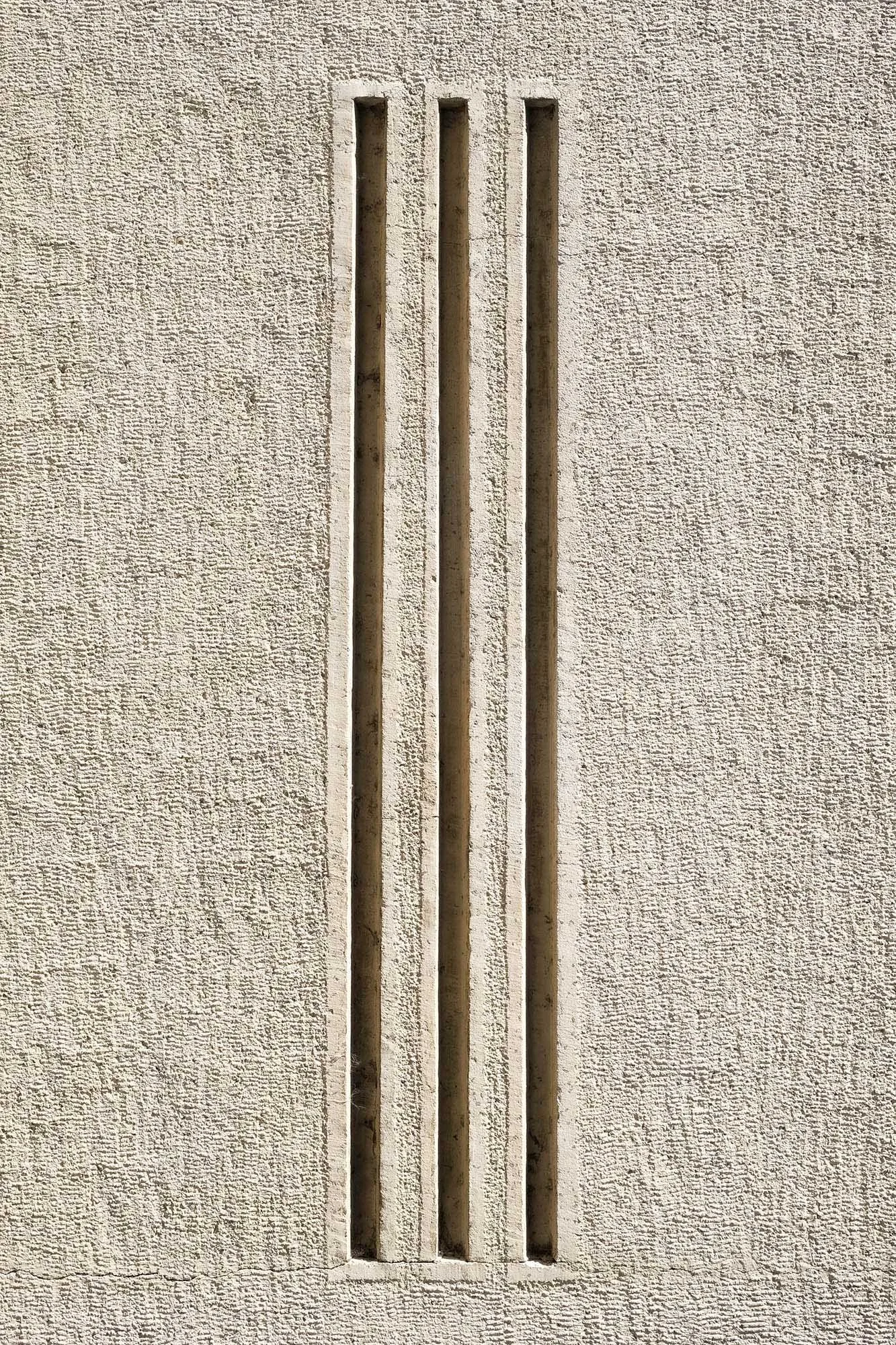 Muro di cemento con tre fessure verticali.