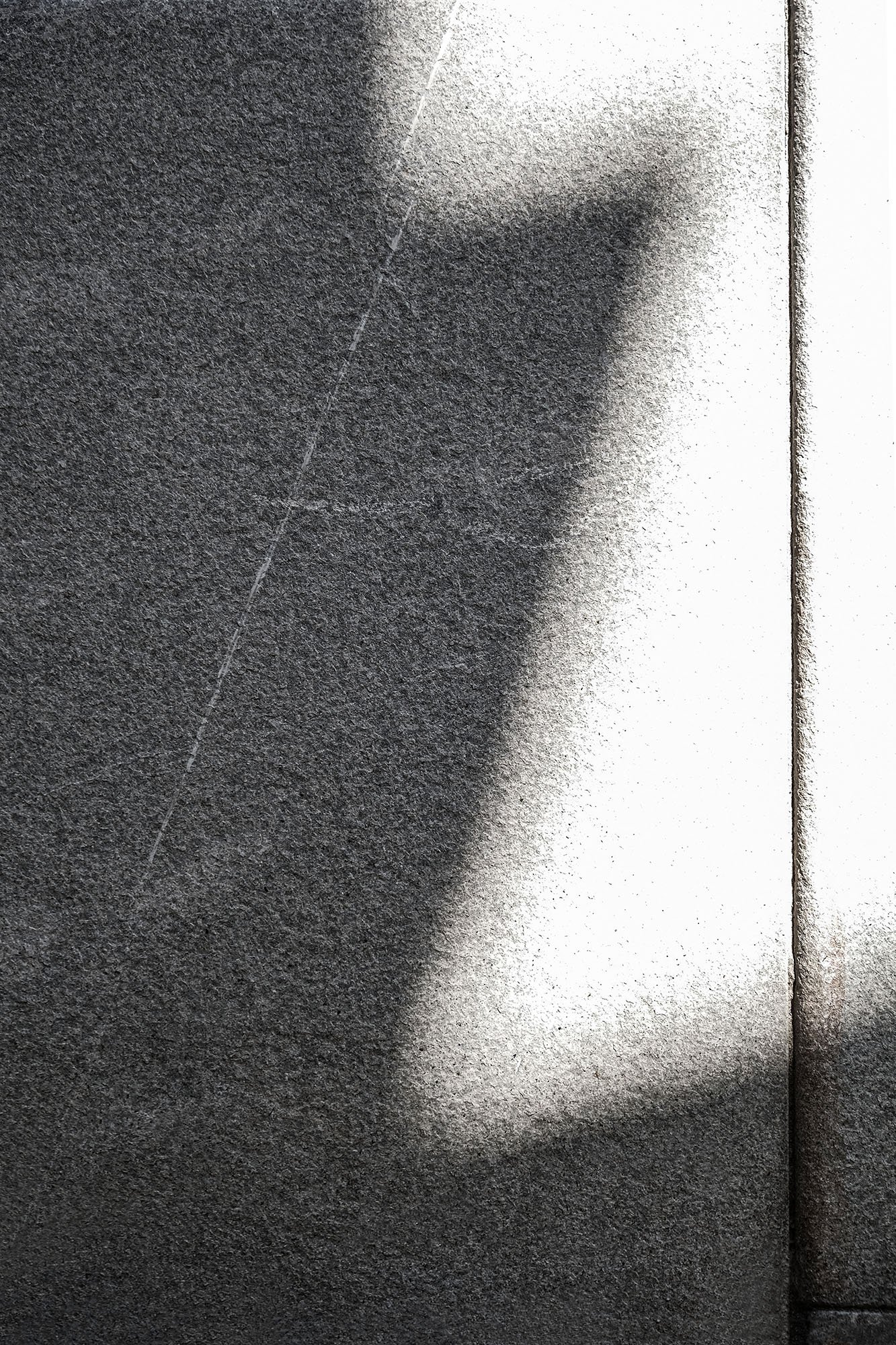 Dettaglio di un muro di cemento con una neuance di colore grigio e nero, con una linea bianca e una linea di giunzione nera al centro.