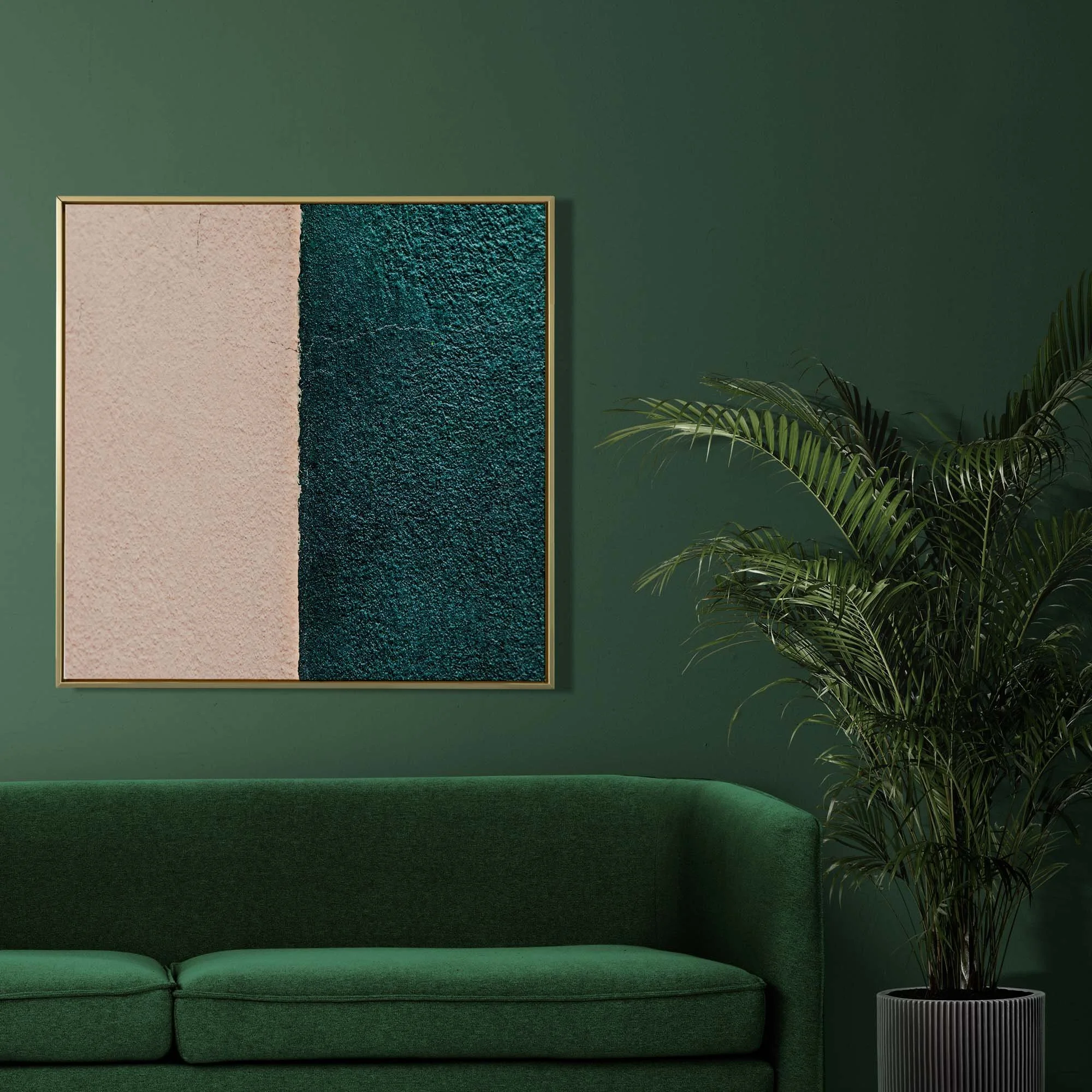 Soggiorno con divano verde scuro, muro verde scuro, quadro con texture color carne e color petrolio, e piante verdi.
