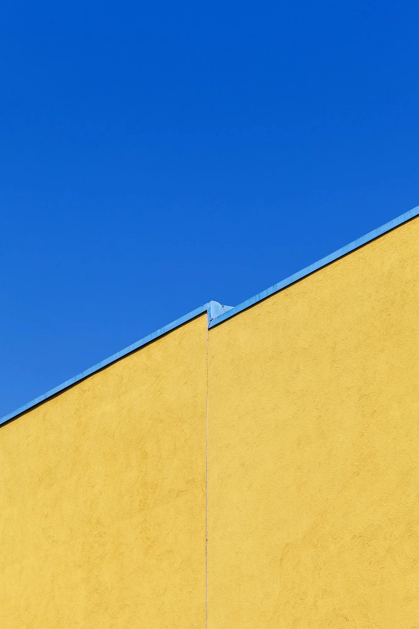 Un edificio con pareti gialle e tetto blu, sotto un cielo azzurro.