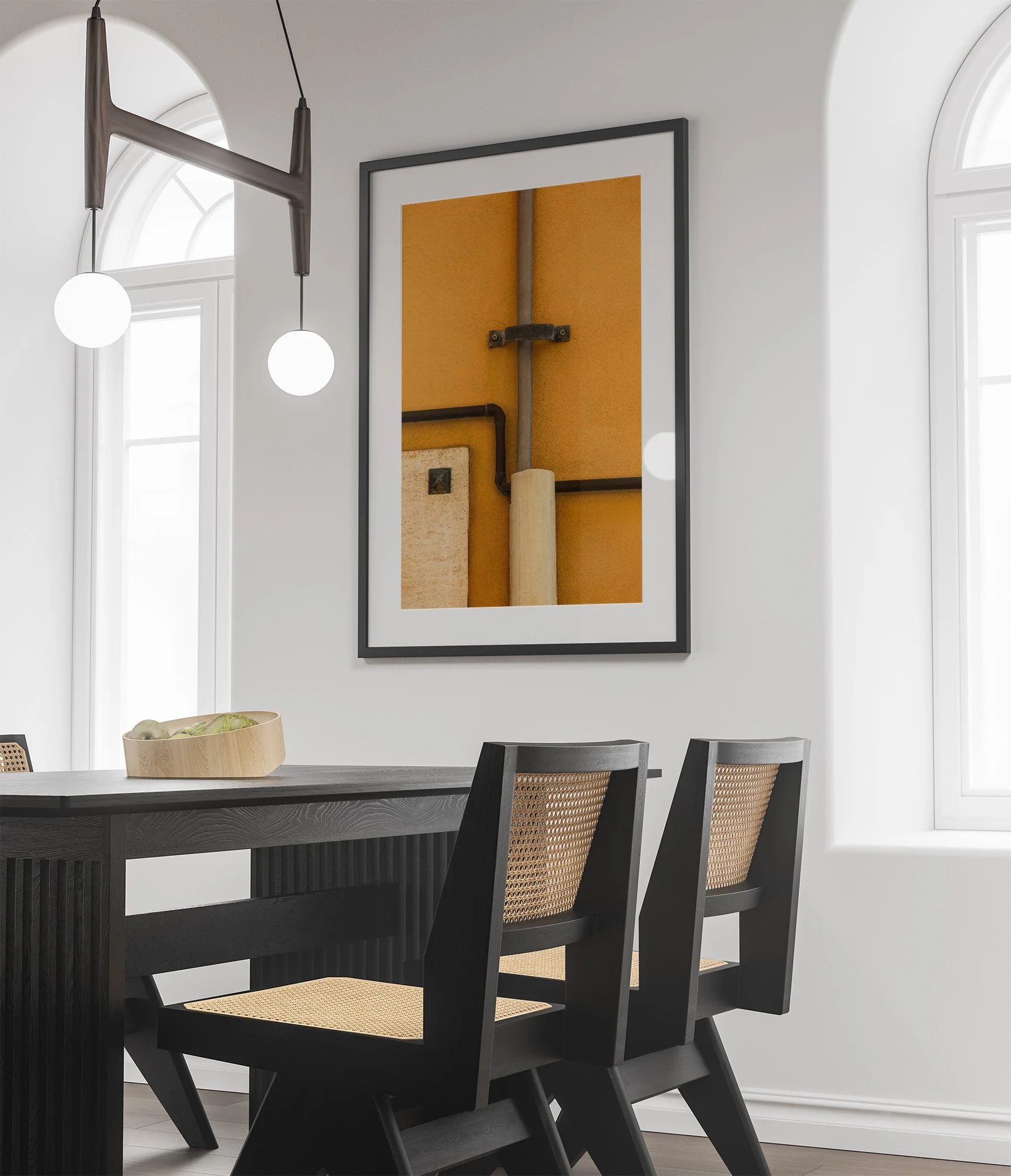 Interno con tavolo nero e sedie con schienali in vimini, pareti bianche, grande specchio e quadro con composizione astratta fatta con tubi, luce naturale da finestra ad arco.