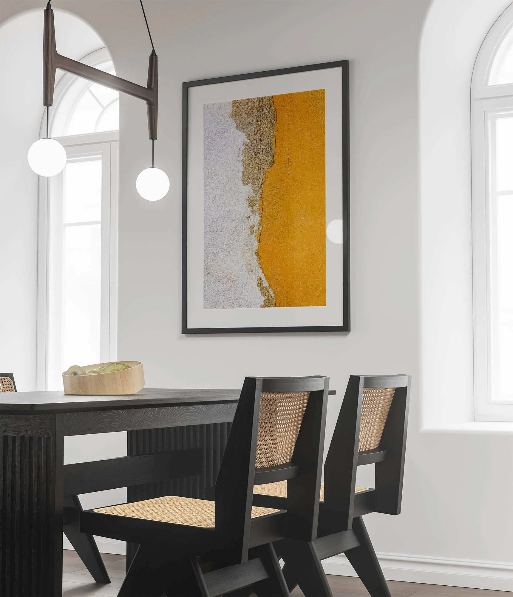 Interno di una sala da pranzo moderna con pareti bianche, una grande finestra ad arco e un quadro astratto con tonalità di giallo ocra e beige. Tavolo nero con sedie con schienali in rattan, e lampade pendenti con globi bianchi.