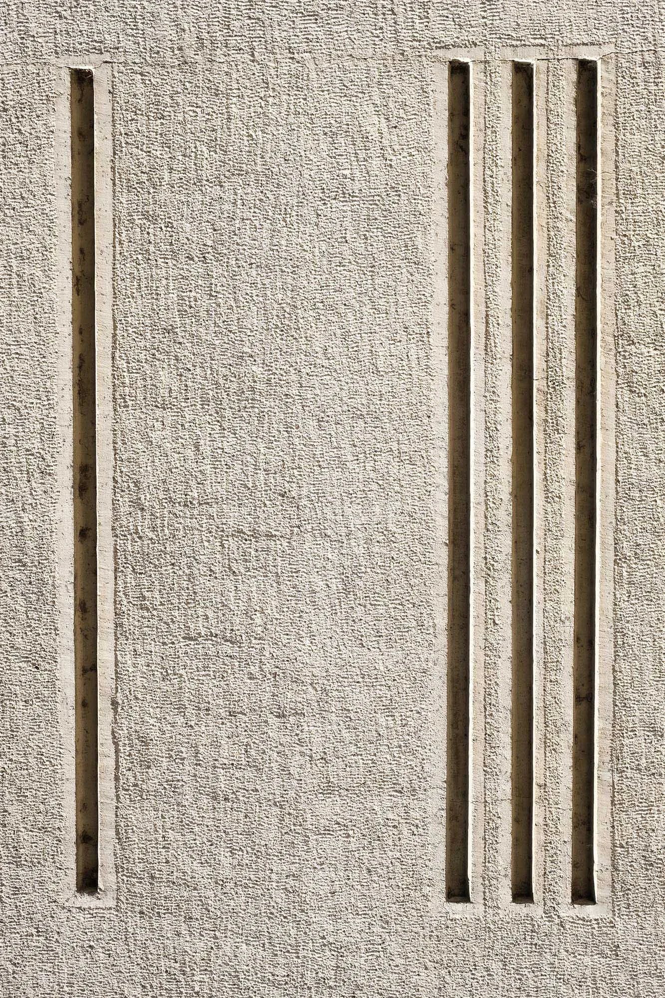 Superficie di una parete in cemento con quattro fessure verticali parallele