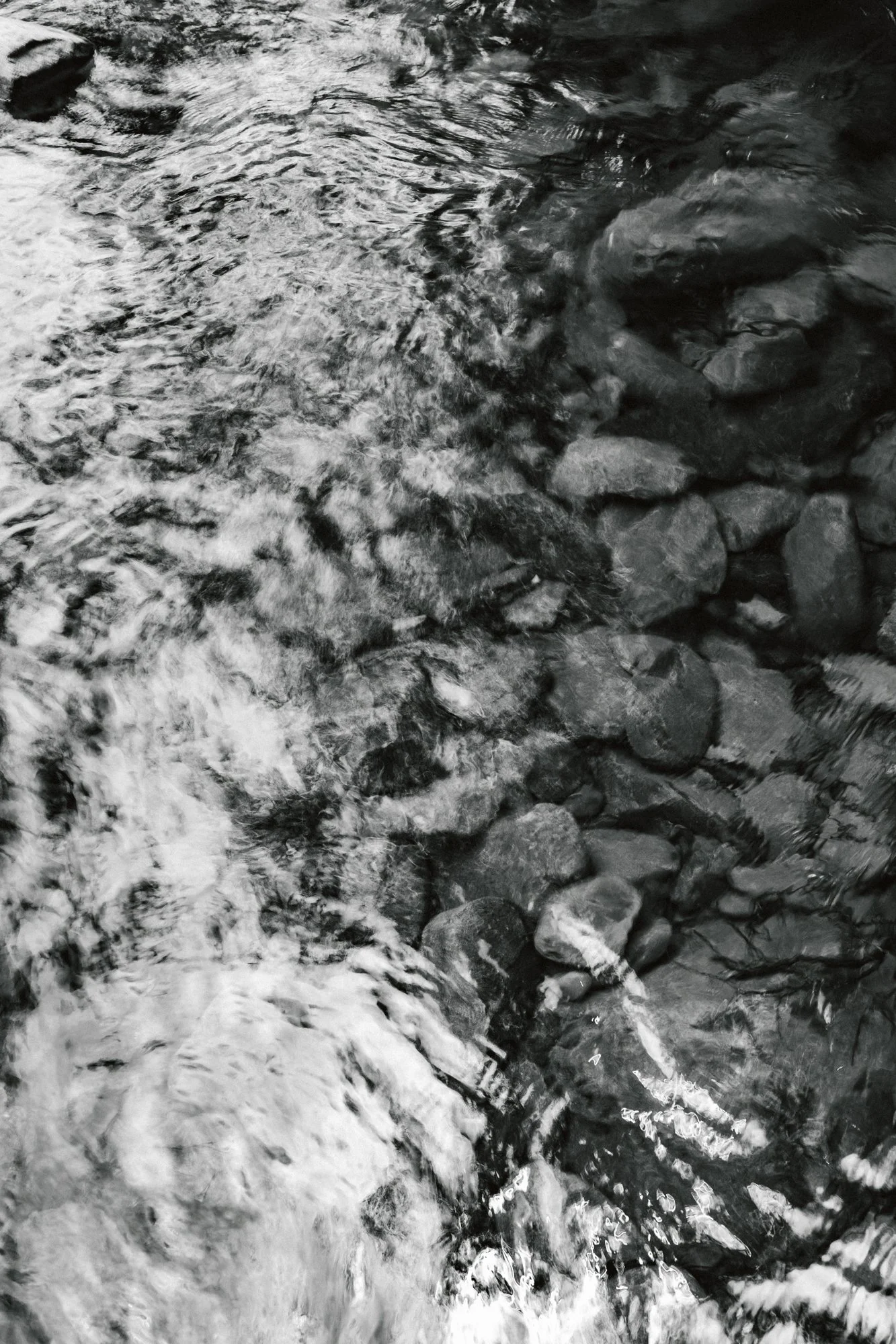 Black and white photograph of a rocky river with water flowing over rocks.