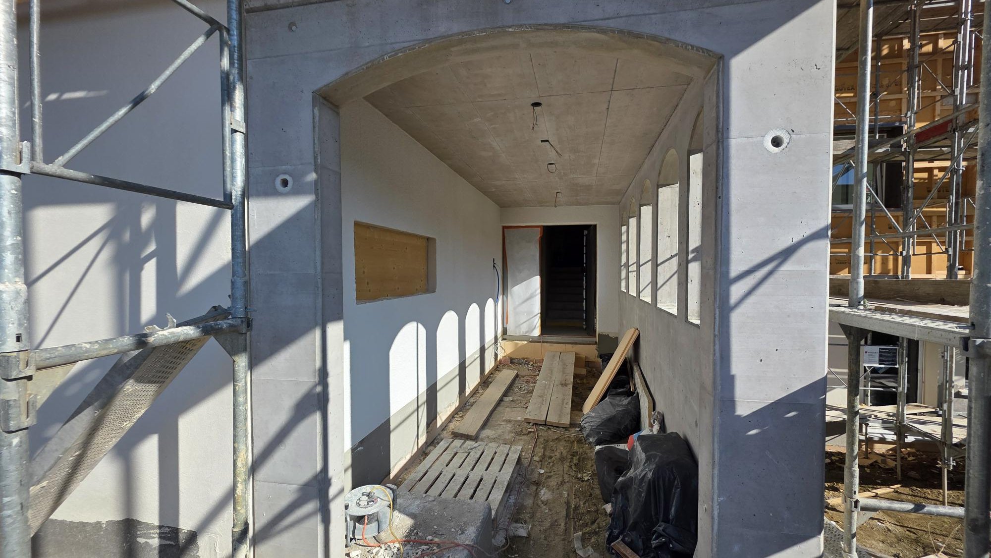 Baustelle mit Rohbau, noch unvollständige Wände, Fensteröffnungen, Gerüste und Baumaterialien