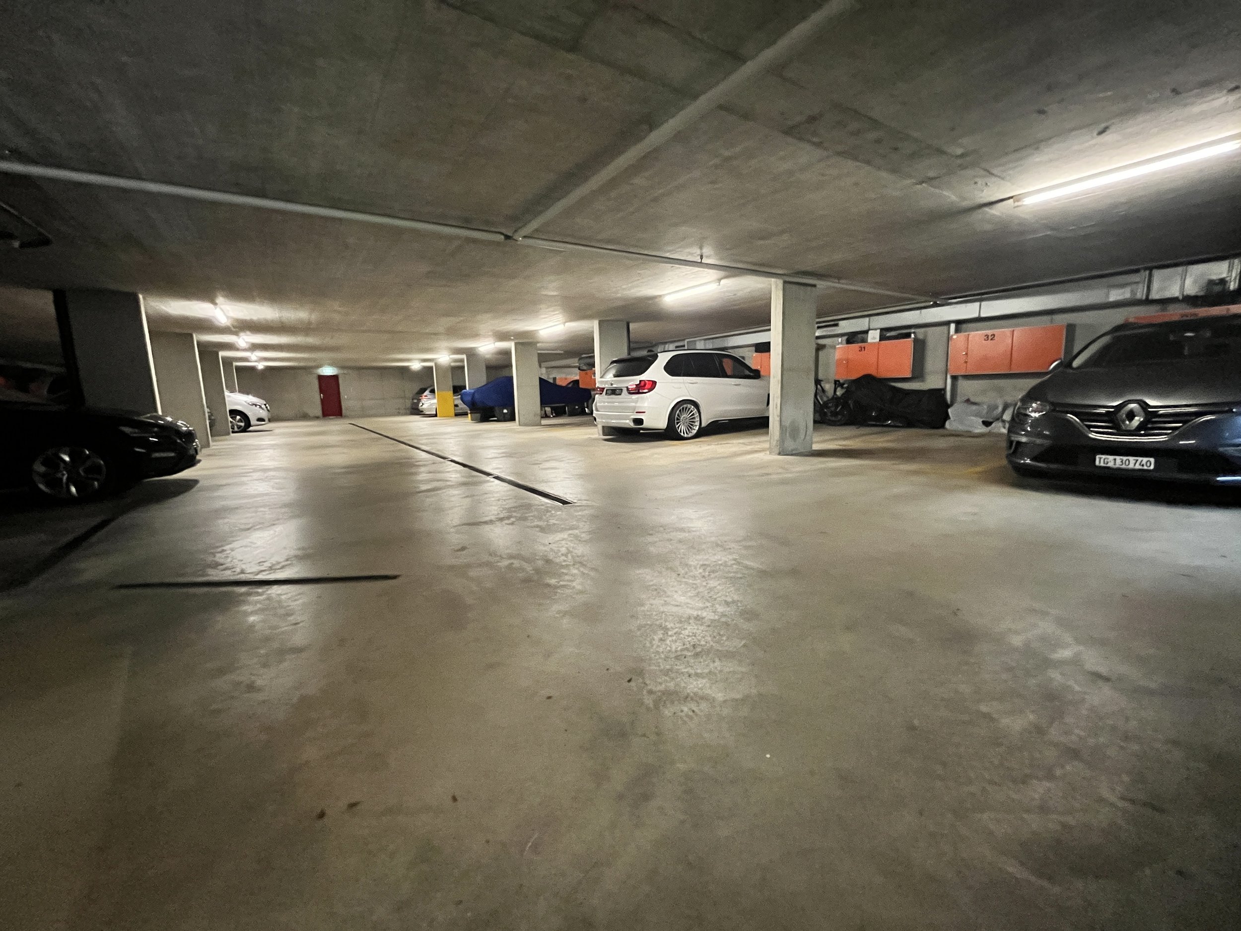 Mehrstöckige Parkgarage mit geparkten Autos, Betonwänden und Deckenlampe